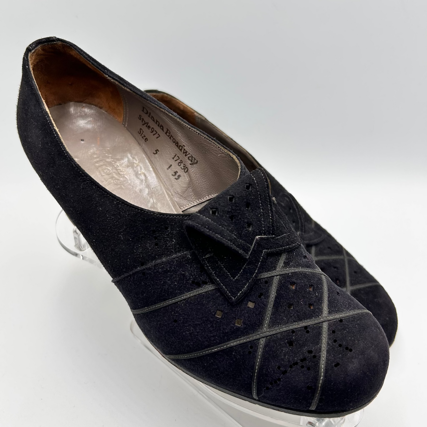 Black suede shoes with decorative lattice pattern on a white background