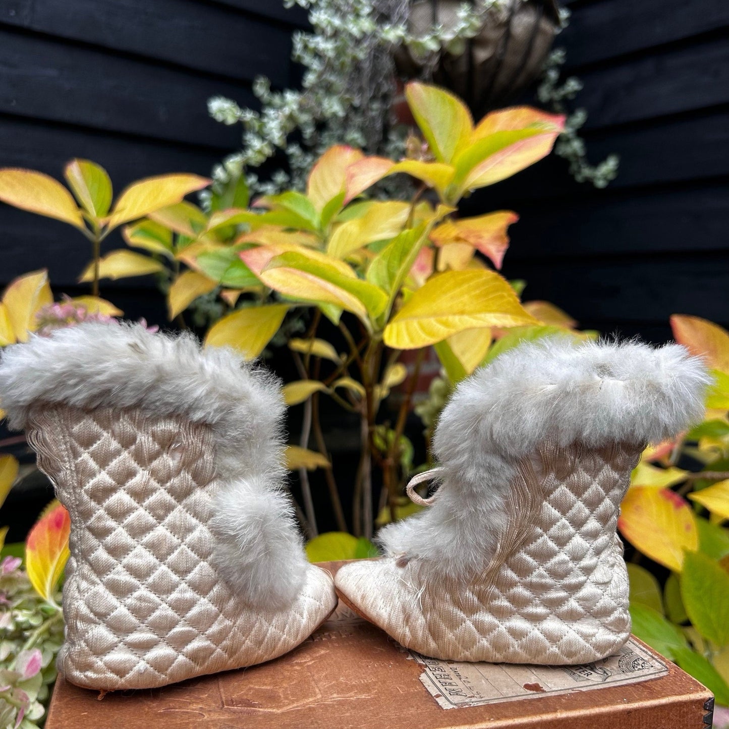 quilted textile fur trimmed silk baby boots on wooden surface with plants behind - Splendid Vintage World