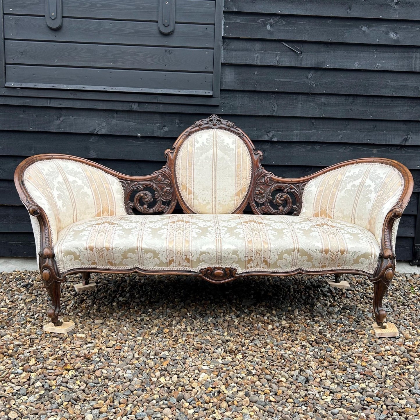 Photo taken in natural light of Victorian carved walnut cameo back sofa chaise upholstered in beautiful traditional damask