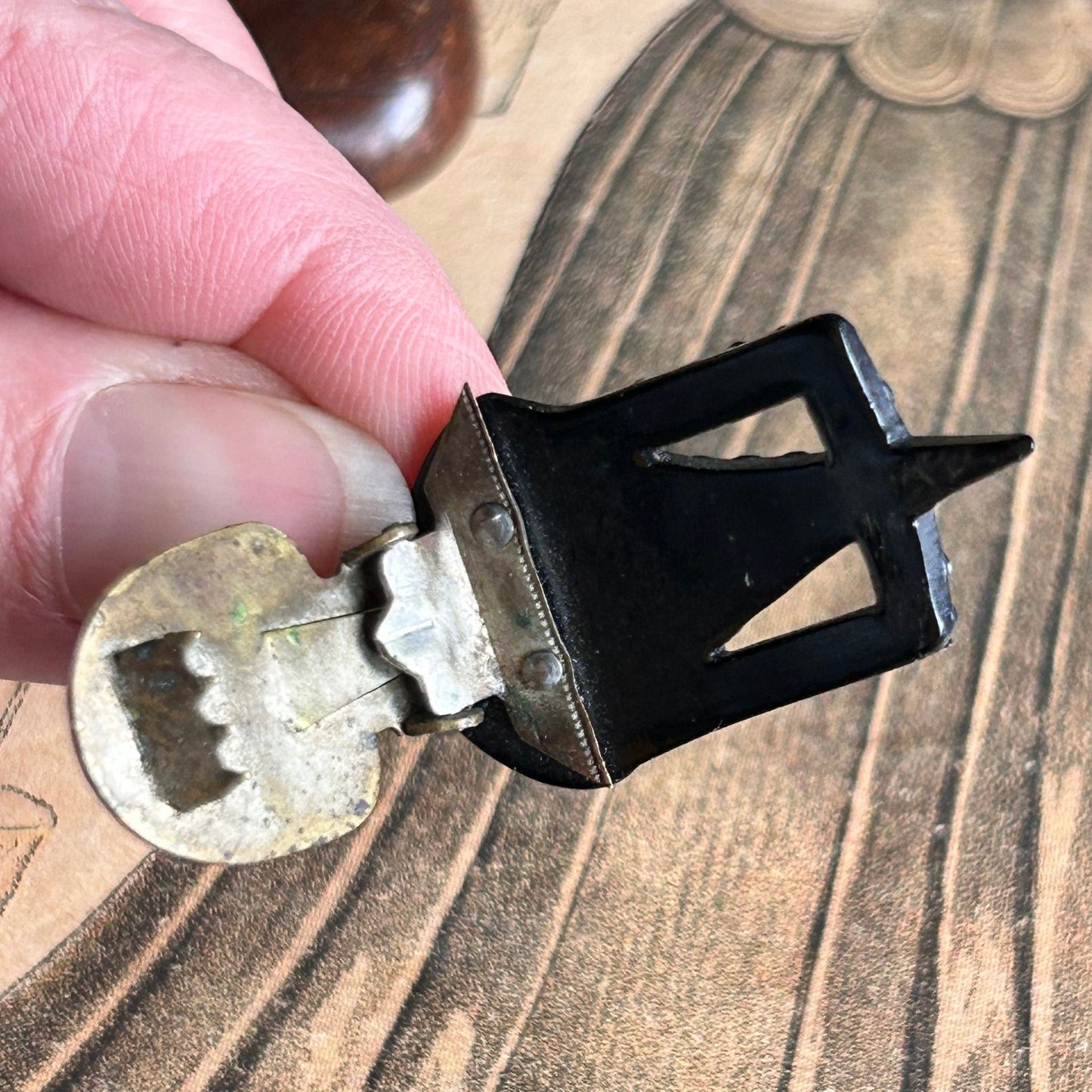 Art Deco 1930s dress clip being held showing the metal back clip above an old illustration - Splendid Vintage World