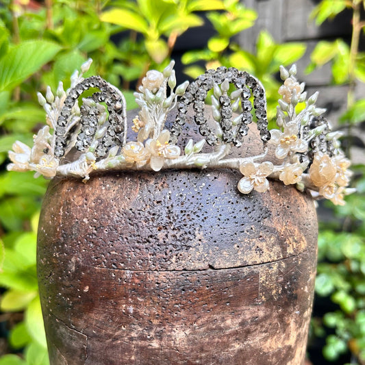 Vintage bridal crown tiara of diamanté, wax flowers & buds on wooden head with greenery behind- Splendid Vintage World