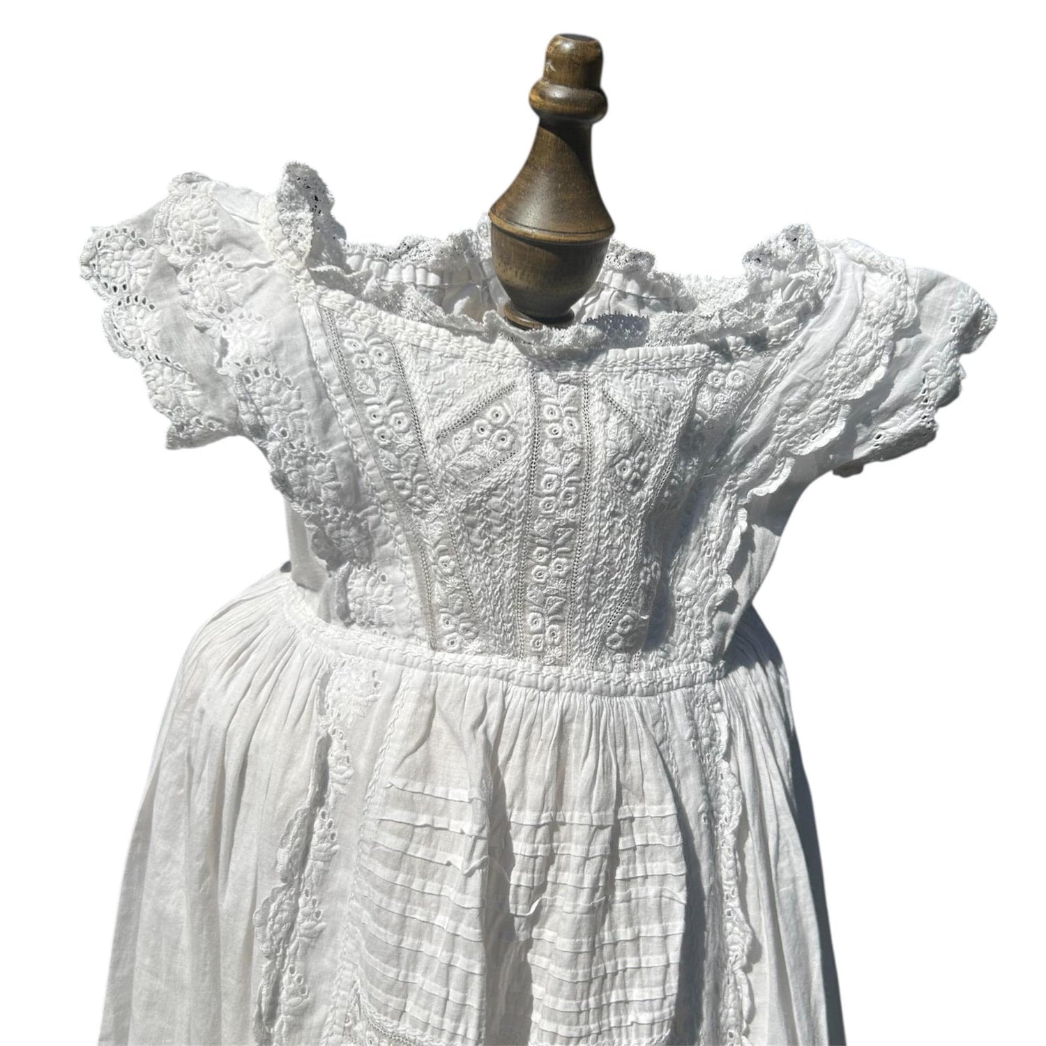 embroidery detail of a white christening gowns bodice & part of the skirt against white background- Splendid Vintage World