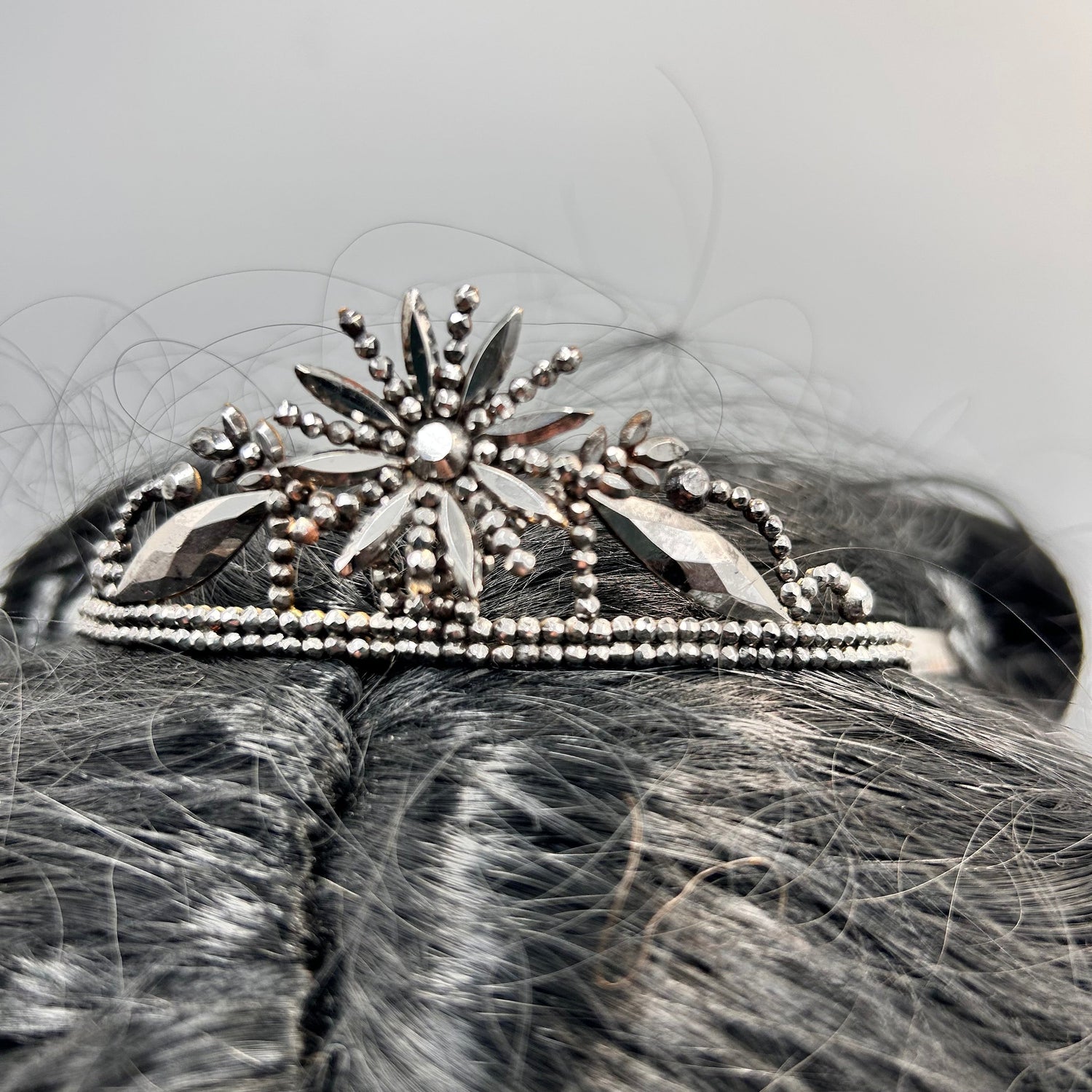 Fine Georgian cut steel floral tiara in black hair against a light grey background - Splendid Vintage World