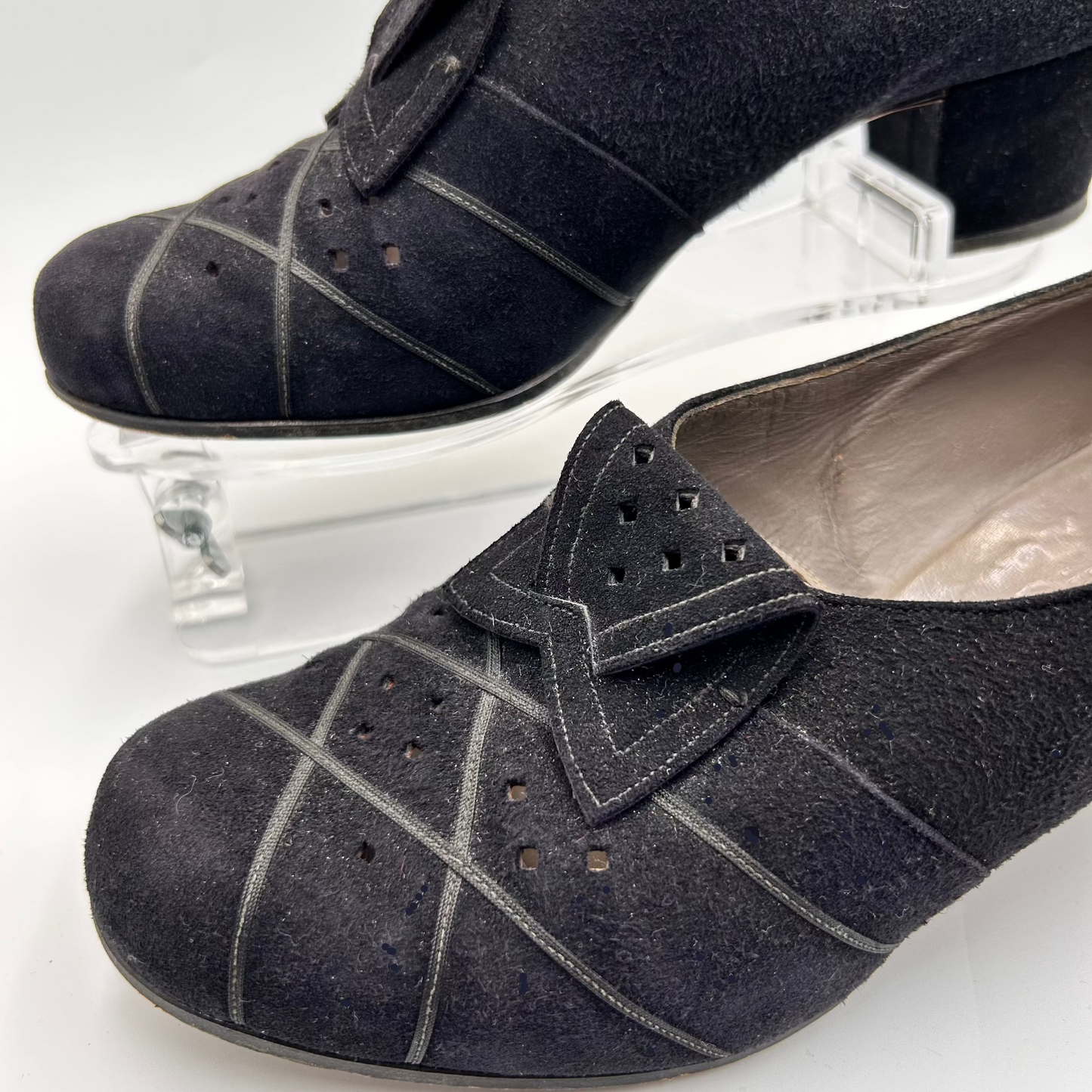 Black suede shoes with decorative bow on a white background