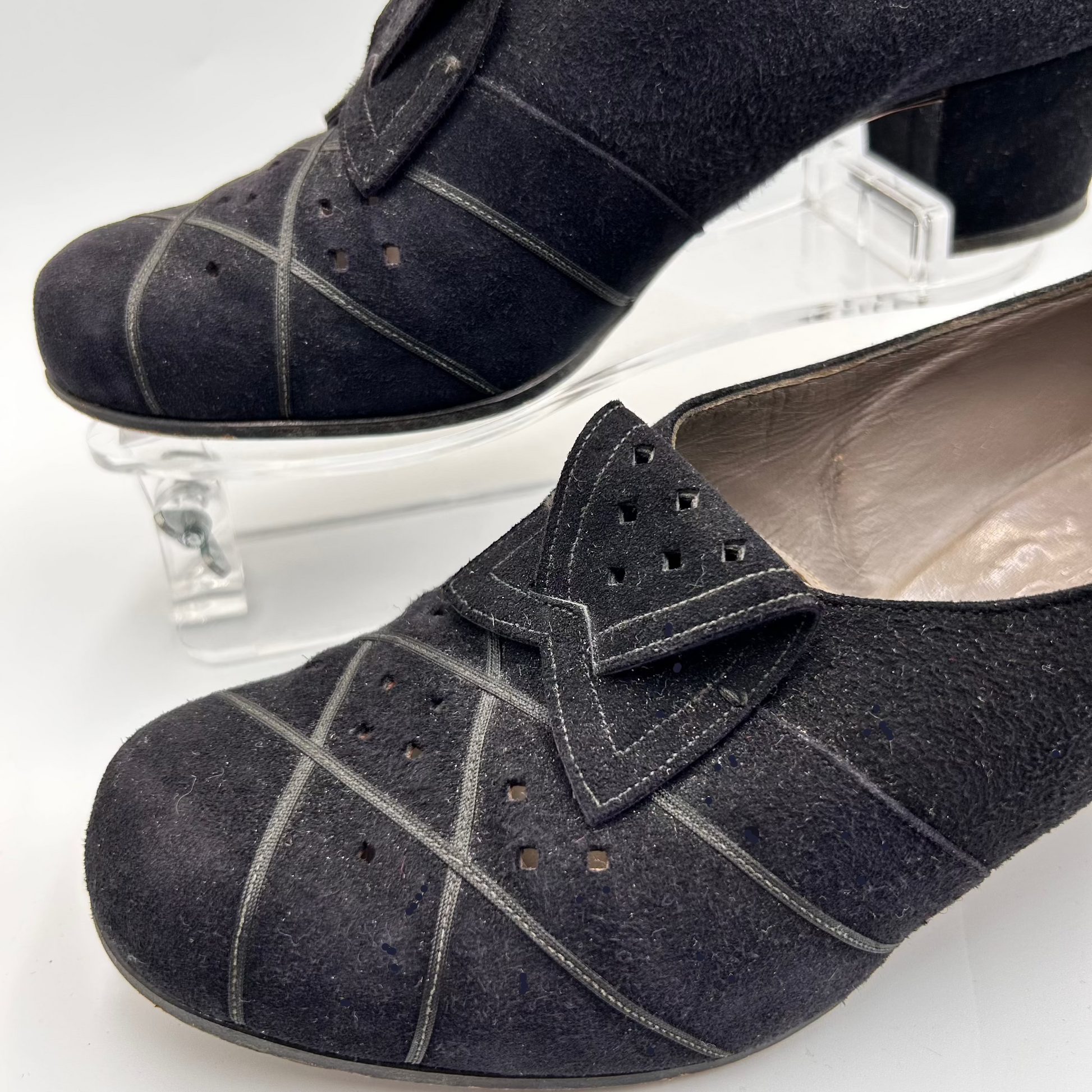 Black suede shoes with decorative bow on a white background