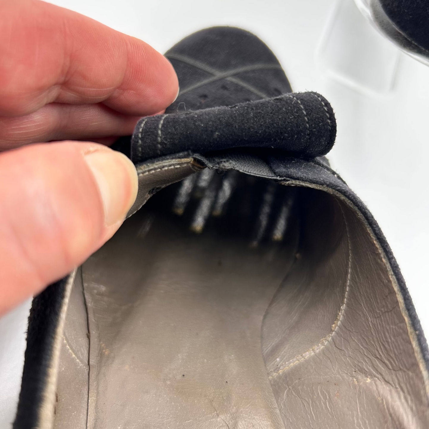 Close-up of a hand holding a shoe showing elastic section under decorative bow.