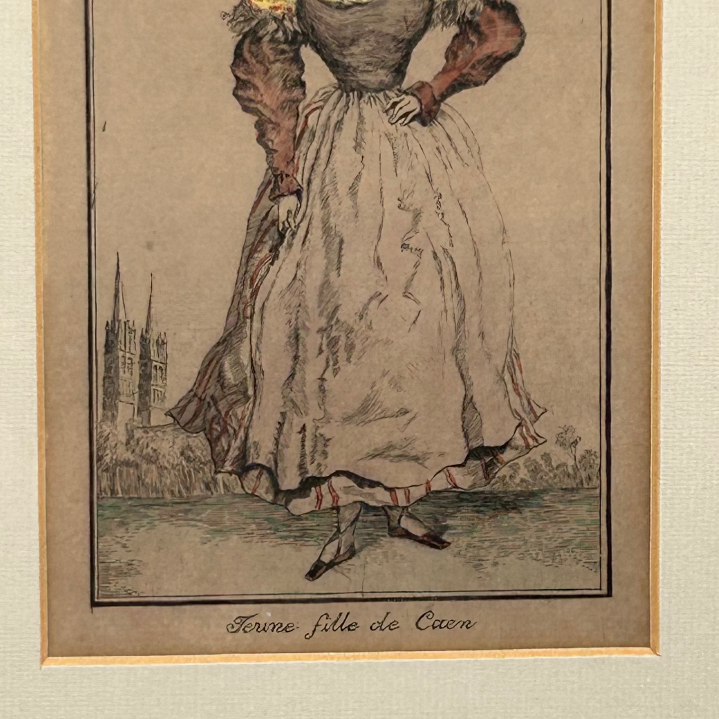 Antique print of a long dress with red sleeves & white skirt with white apron titled Jeune fille de Caen, & church spires
