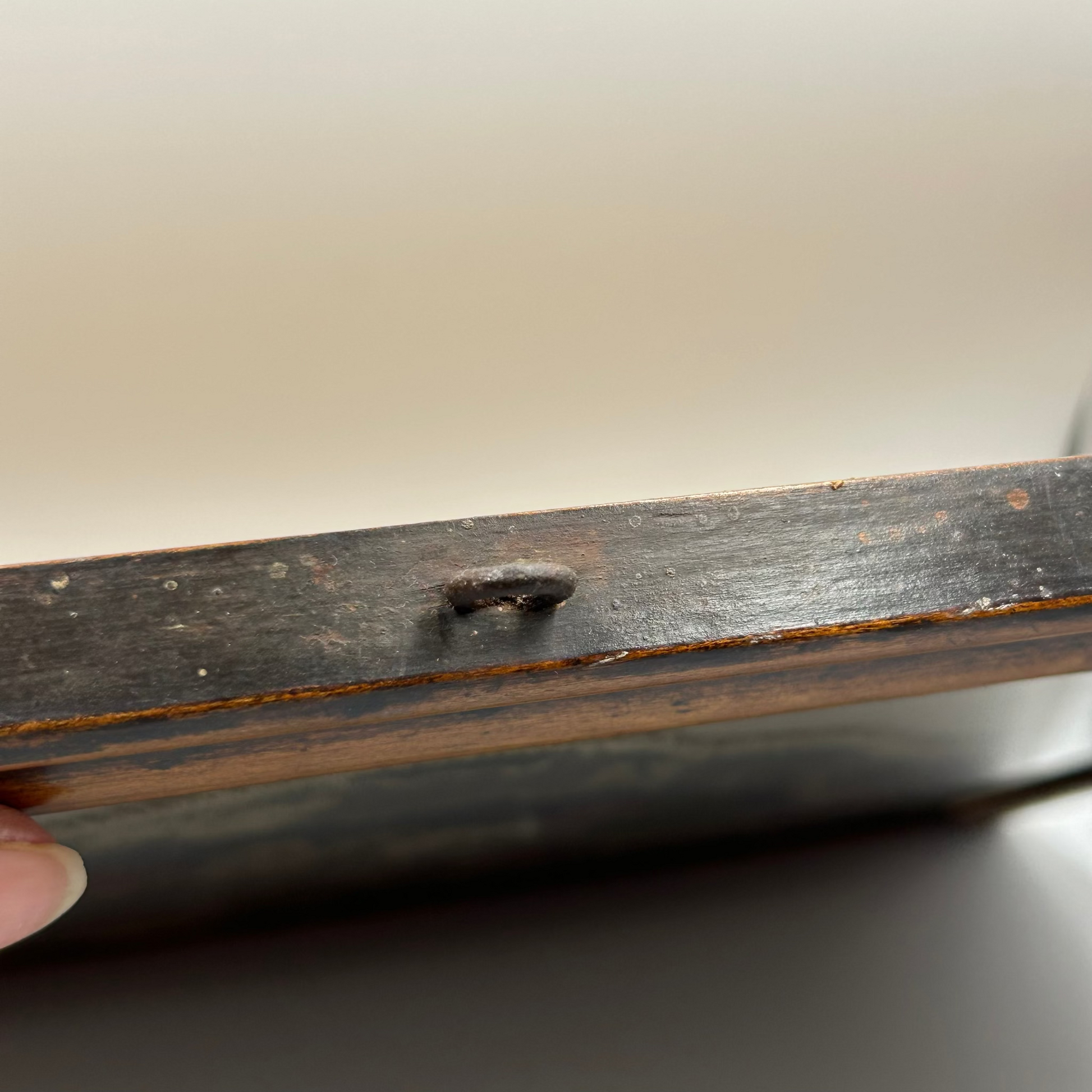 Close-up of a wooden frame with a hand holding it, on a neutral background