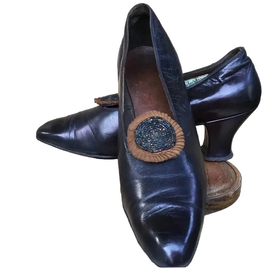 A pair of dark purple Antique 1910s Shoes with beaded rosettes on wooden base on white background - Splendid Vintage World