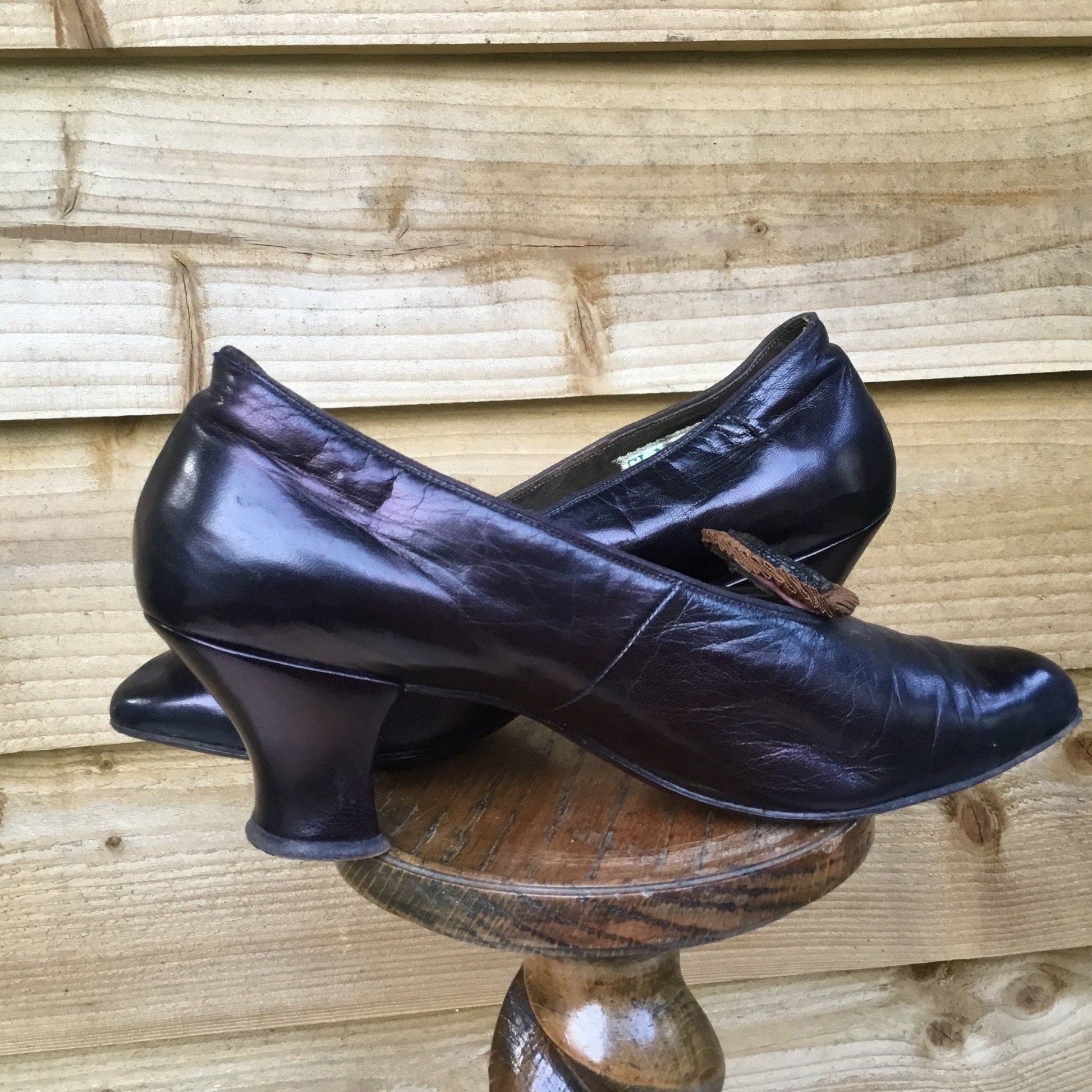 pair of Antique Leather Shoes with beaded rosettes on wooden stand with wood slat background - Splendid Vintage World