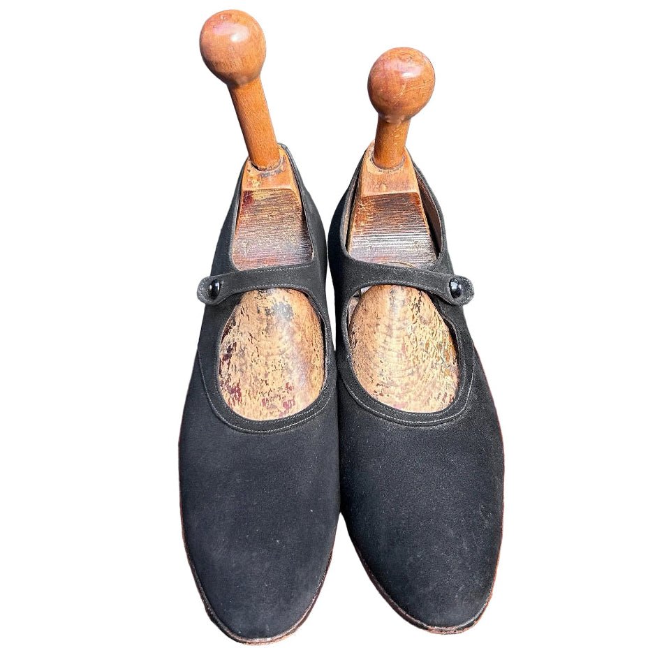front view of Antique 1920’s black suede shoes  with wooden trees against white background - Splendid Vintage World