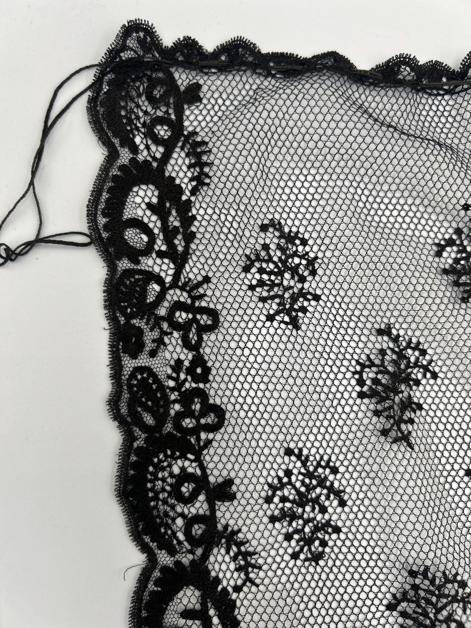 Antique black lace bonnet veil, lace panel with drawstring close up detail on white background