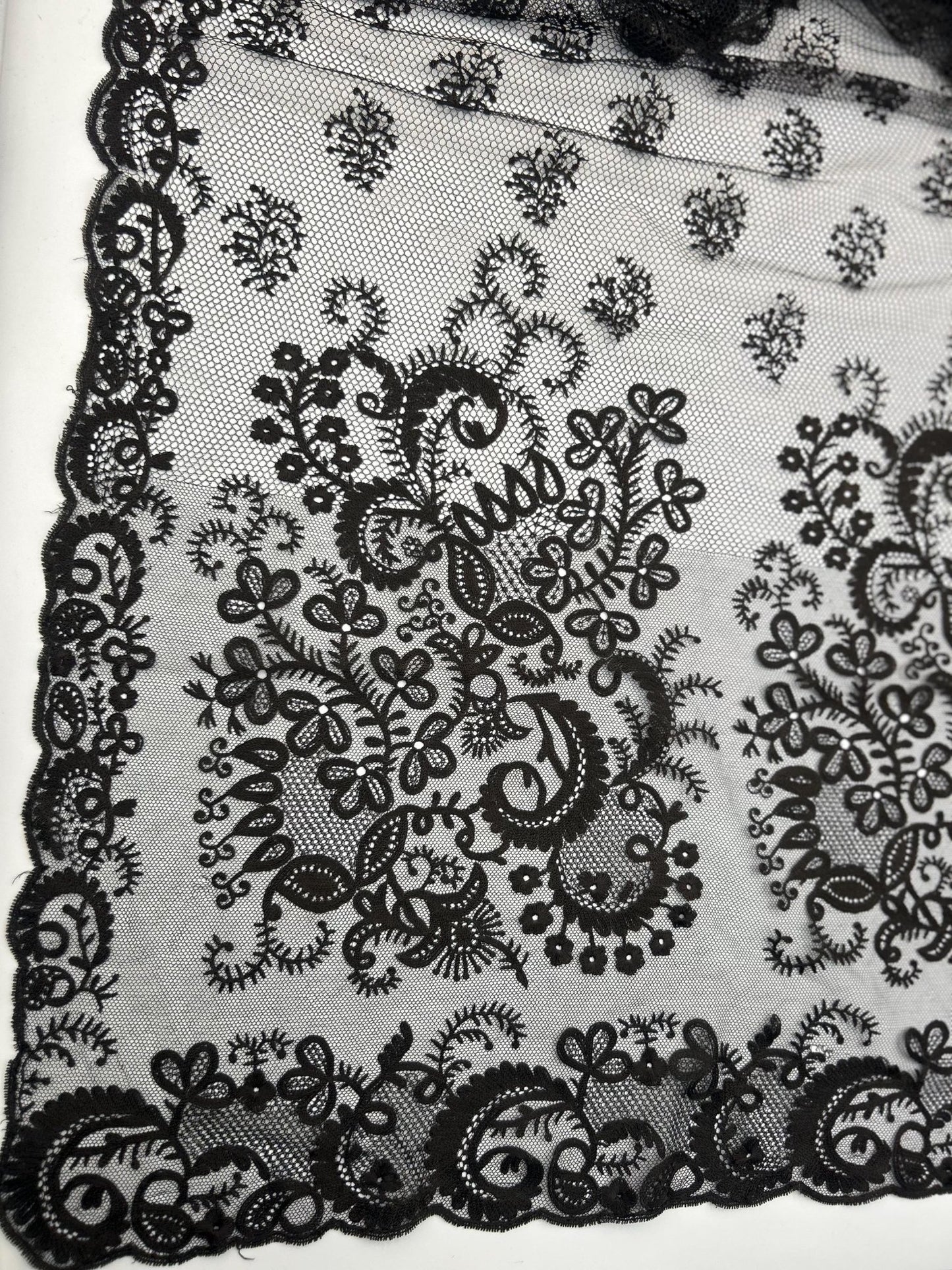 Antique black lace bonnet veil, apron, lace panel with drawstring floral detail close up against white background
