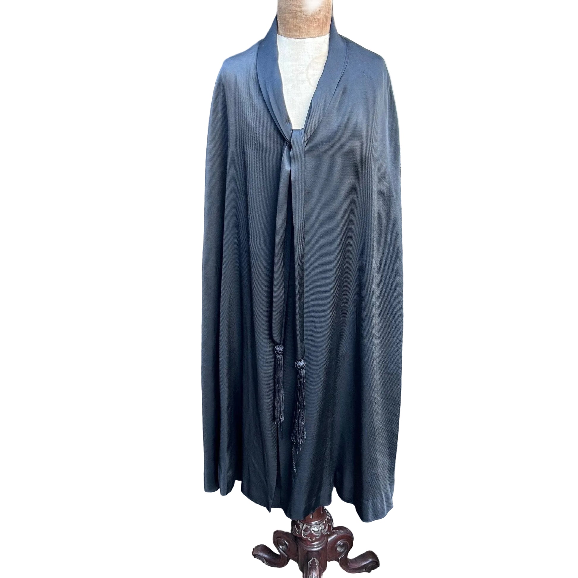 Antique 1920s black silk opera cape with tie neckline to front on mannequin against white background- Splendid Vintage World