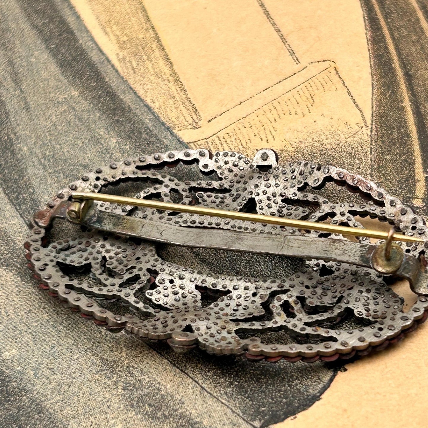 back of Antique butterfly brooch of cut steel pinned construction on printed magazine - Splendid Vintage World