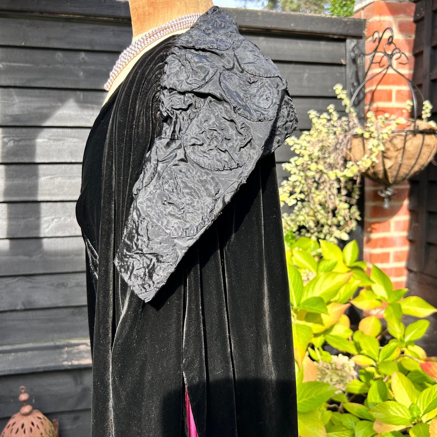 Art Deco black velvet cocoon cape with feature collar side view in garden setting - Splendid Vintage World
