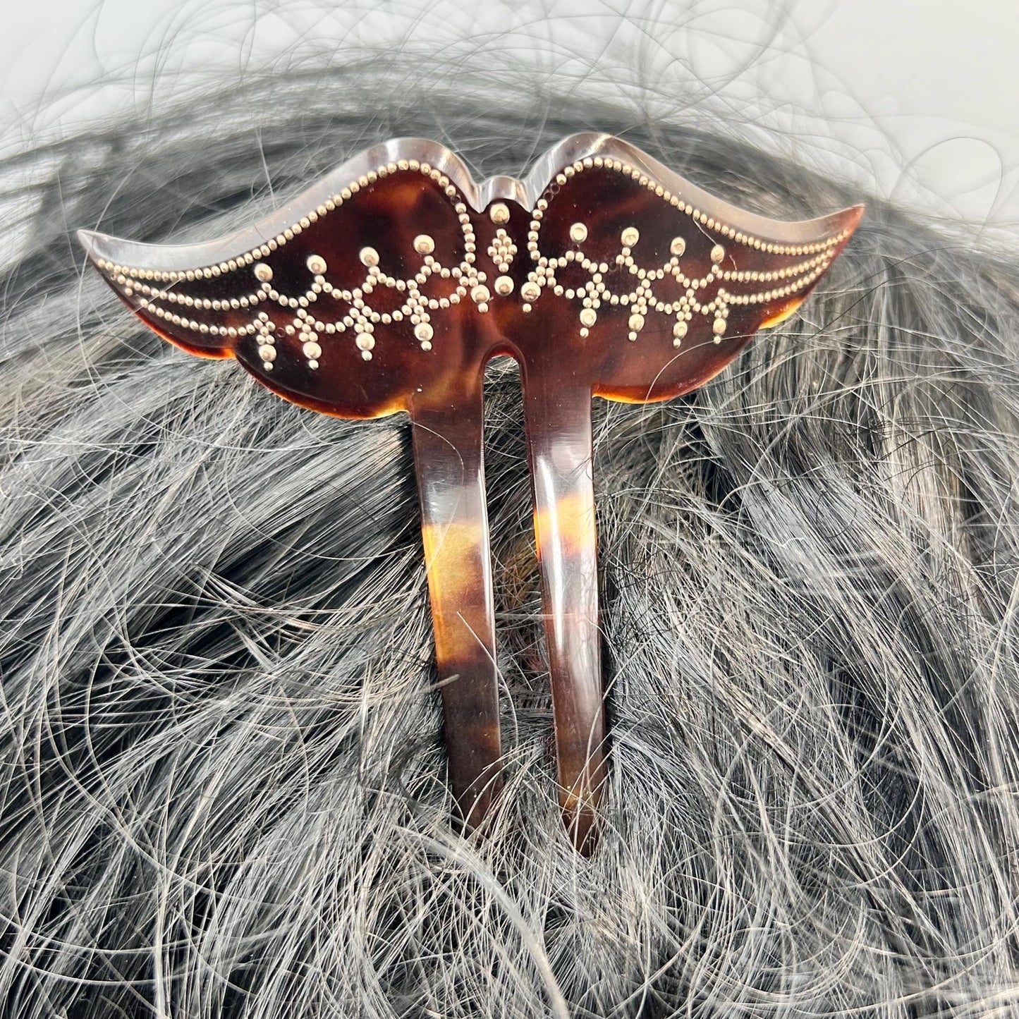 Edwardian faux tortoiseshell hair pin decoration in black hair against grey background - Splendid Vintage World