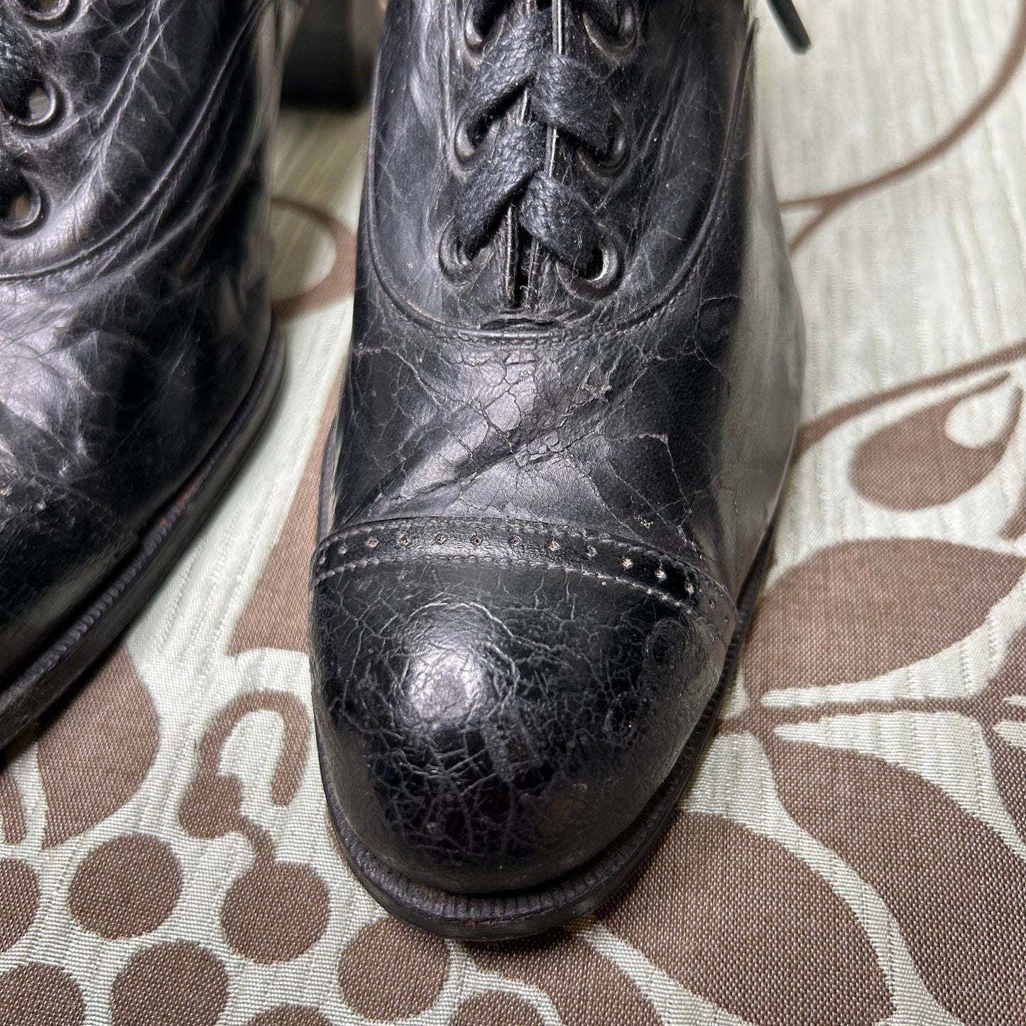 close up of toes on Edwardian Ladies black leather lace up Oxford shoes on patterned fabric - Splendid Vintage World