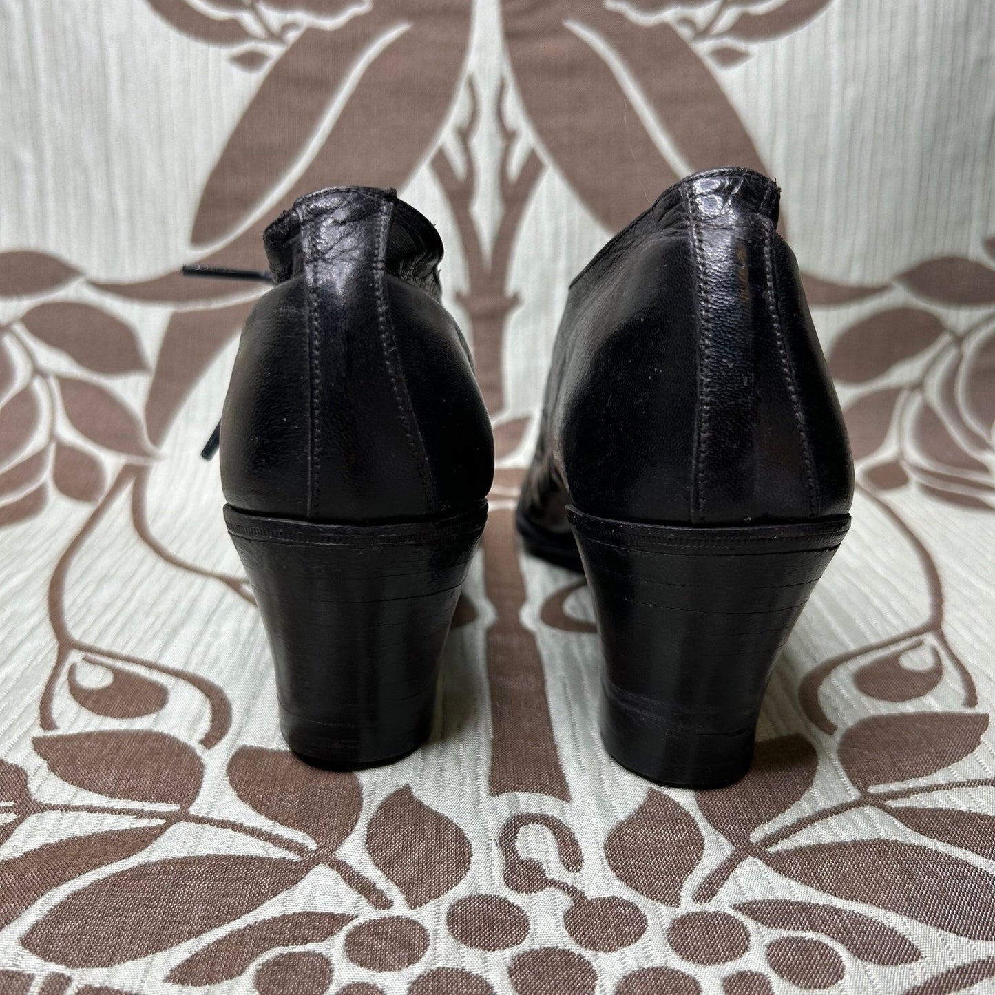back heel view of Edwardian Ladies black leather Oxford heeled shoes on patterned fabric - Splendid Vintage World