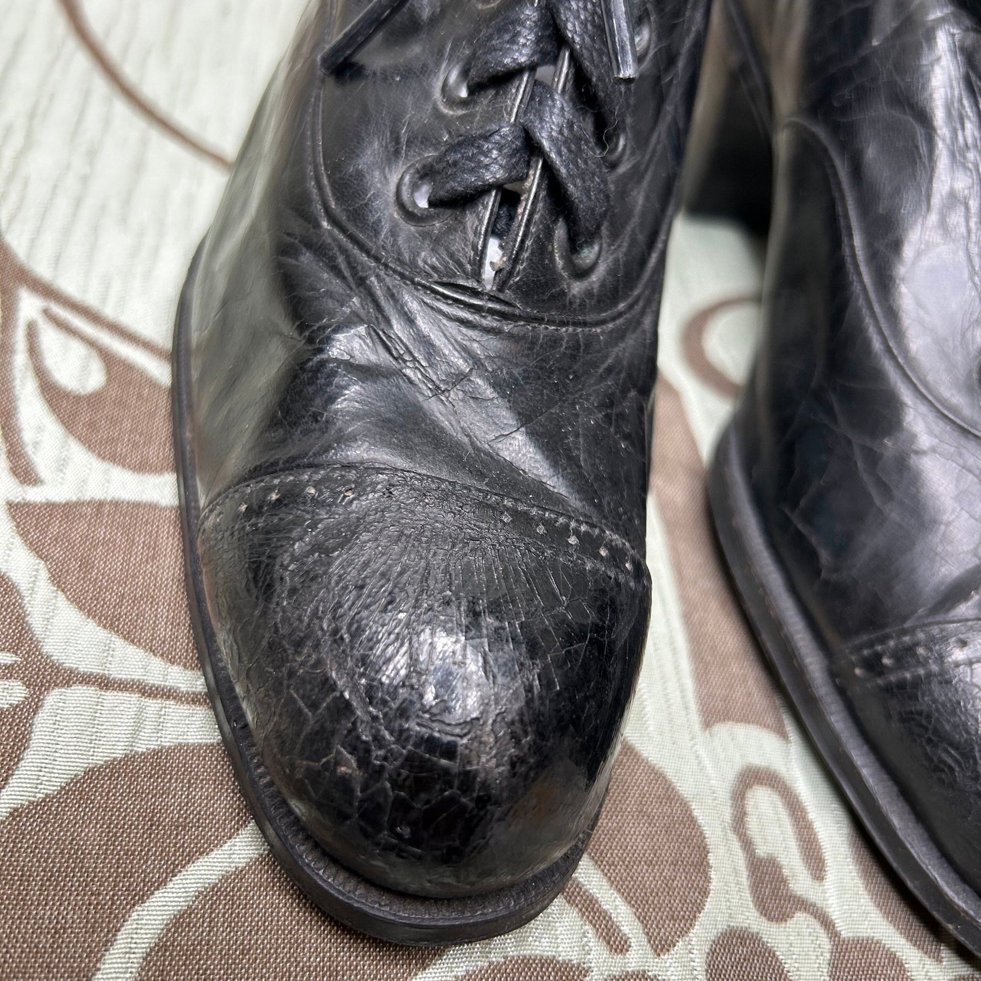 close up of toe on Edwardian Ladies black leather lace up Oxford shoes on patterned fabric - Splendid Vintage World