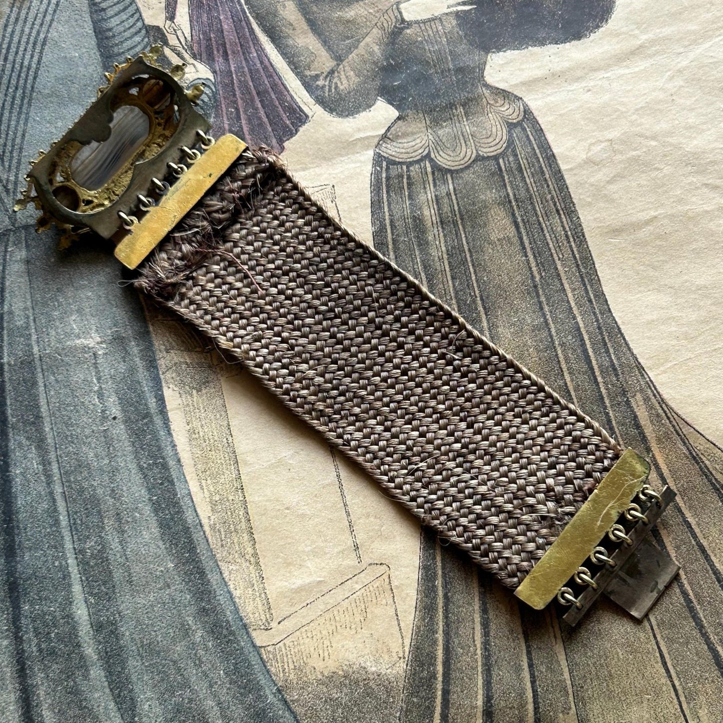 reverse view of Antique Georgian Woven Hair Cuff Bracelet Gilt Metal on printed magazine - Splendid Vintage World