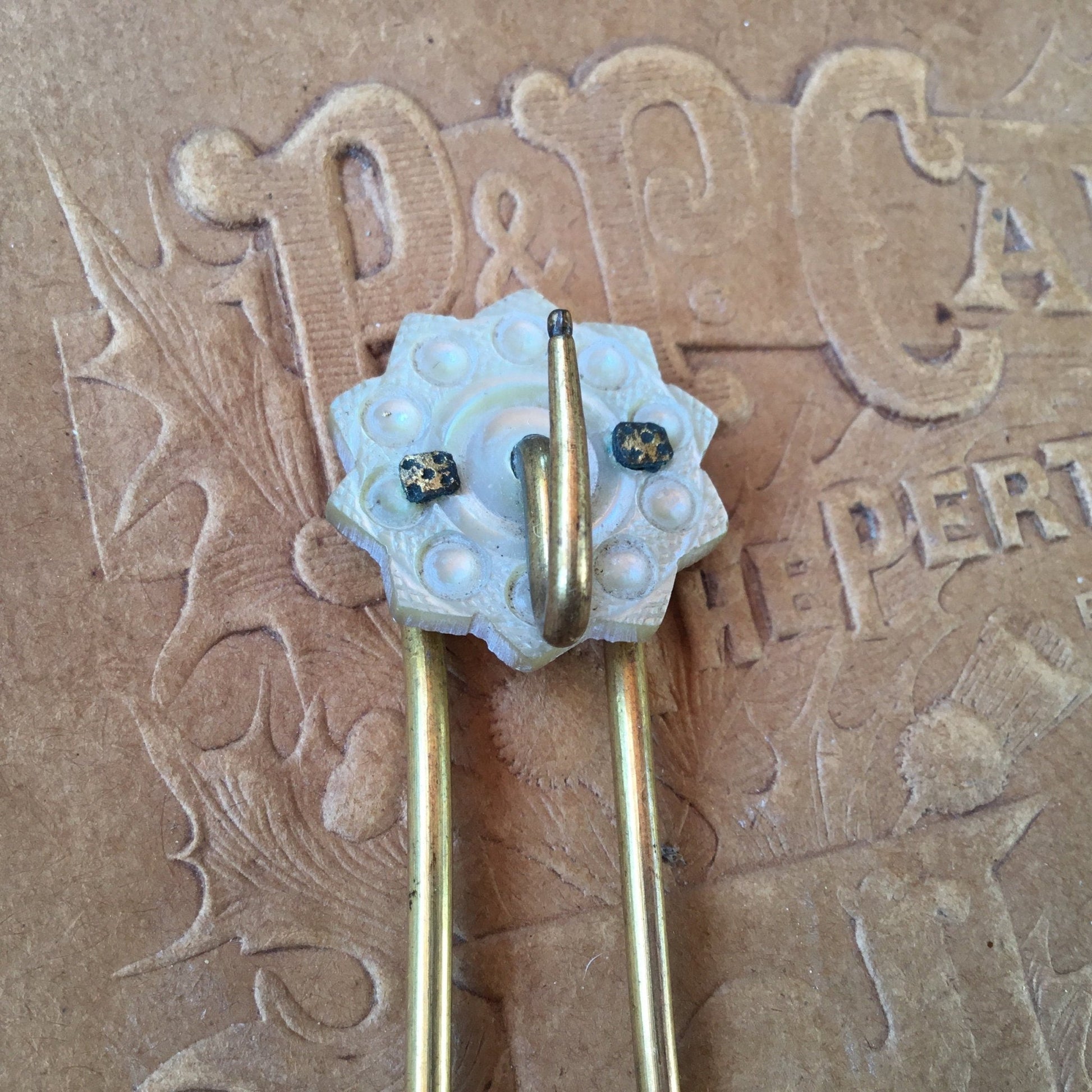 Mother of Pearl flower shaped disc with 2 rivets & gold colour hook & 2 gold prongs on brown backing - Splendid Vintage World