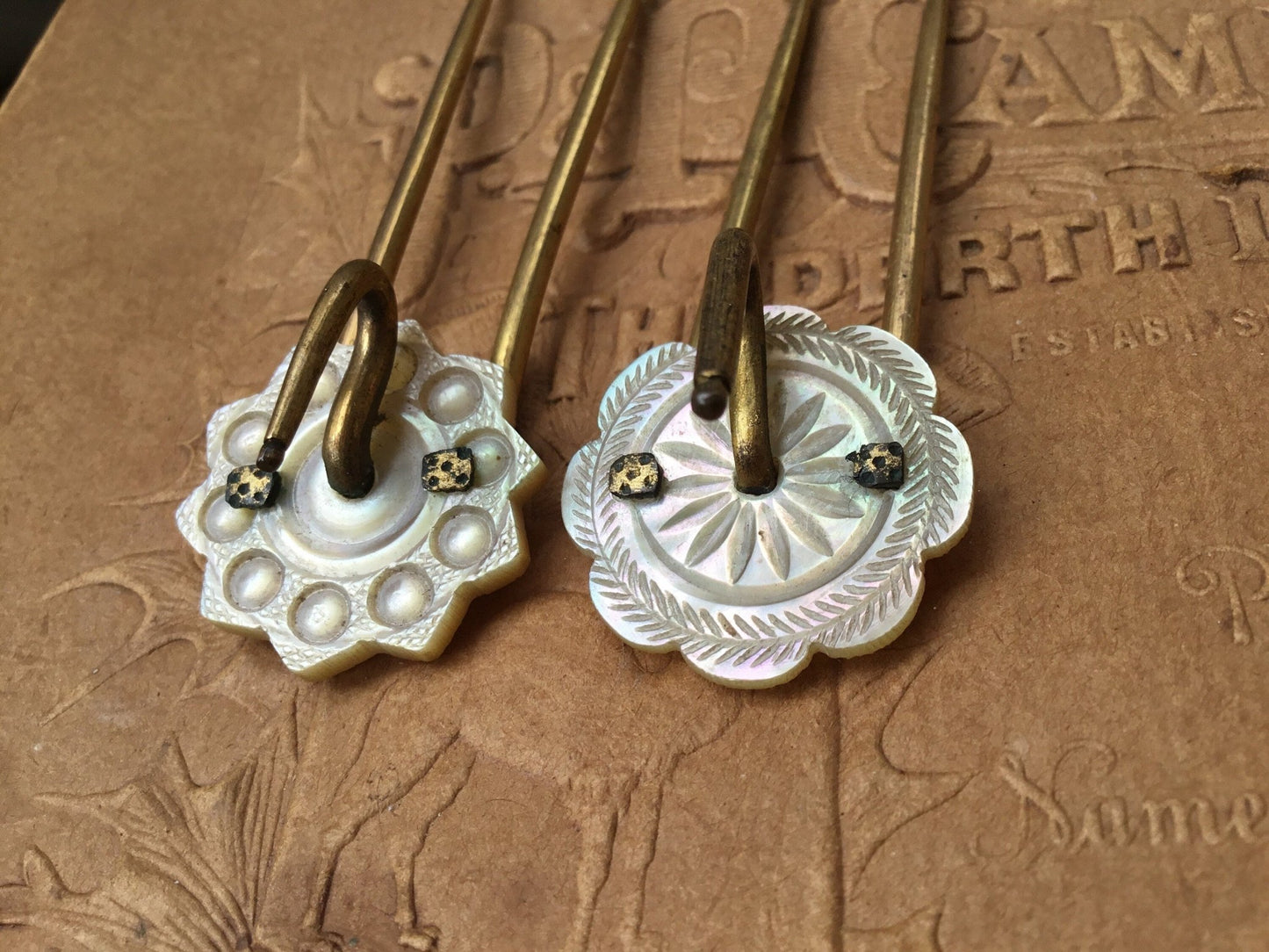 old coloured Hair pins with mother of pearl circular top on textured brown background - Splendid Vintage World