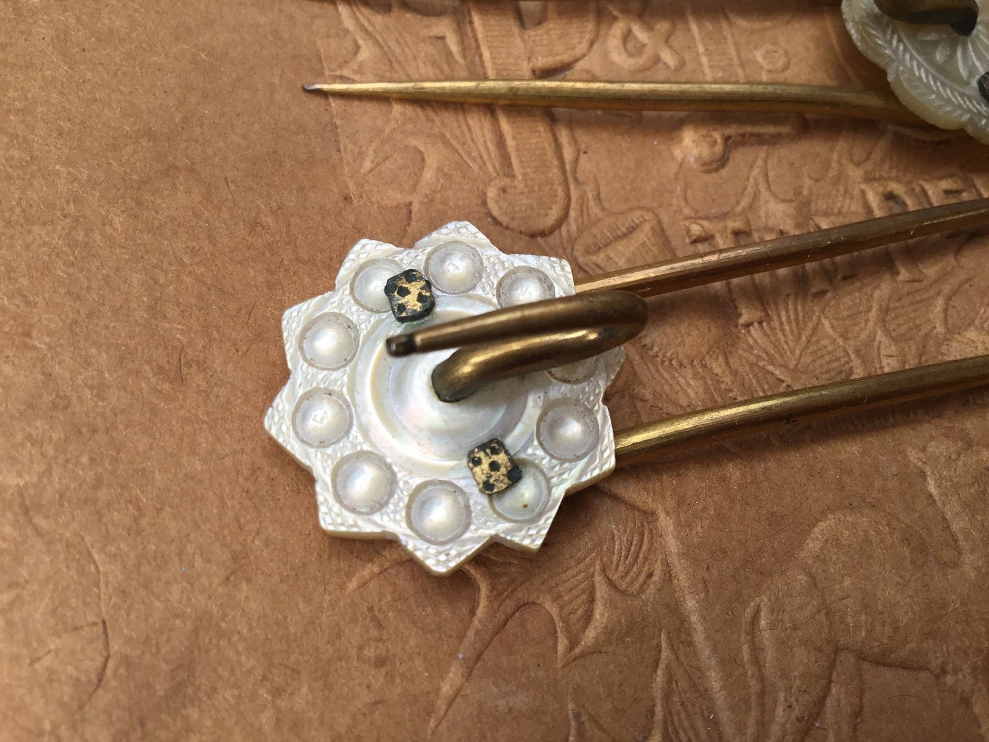 Gilded metal prongs with Mother of Pearl flower shaped top on textured brown background - Splendid Vintage World