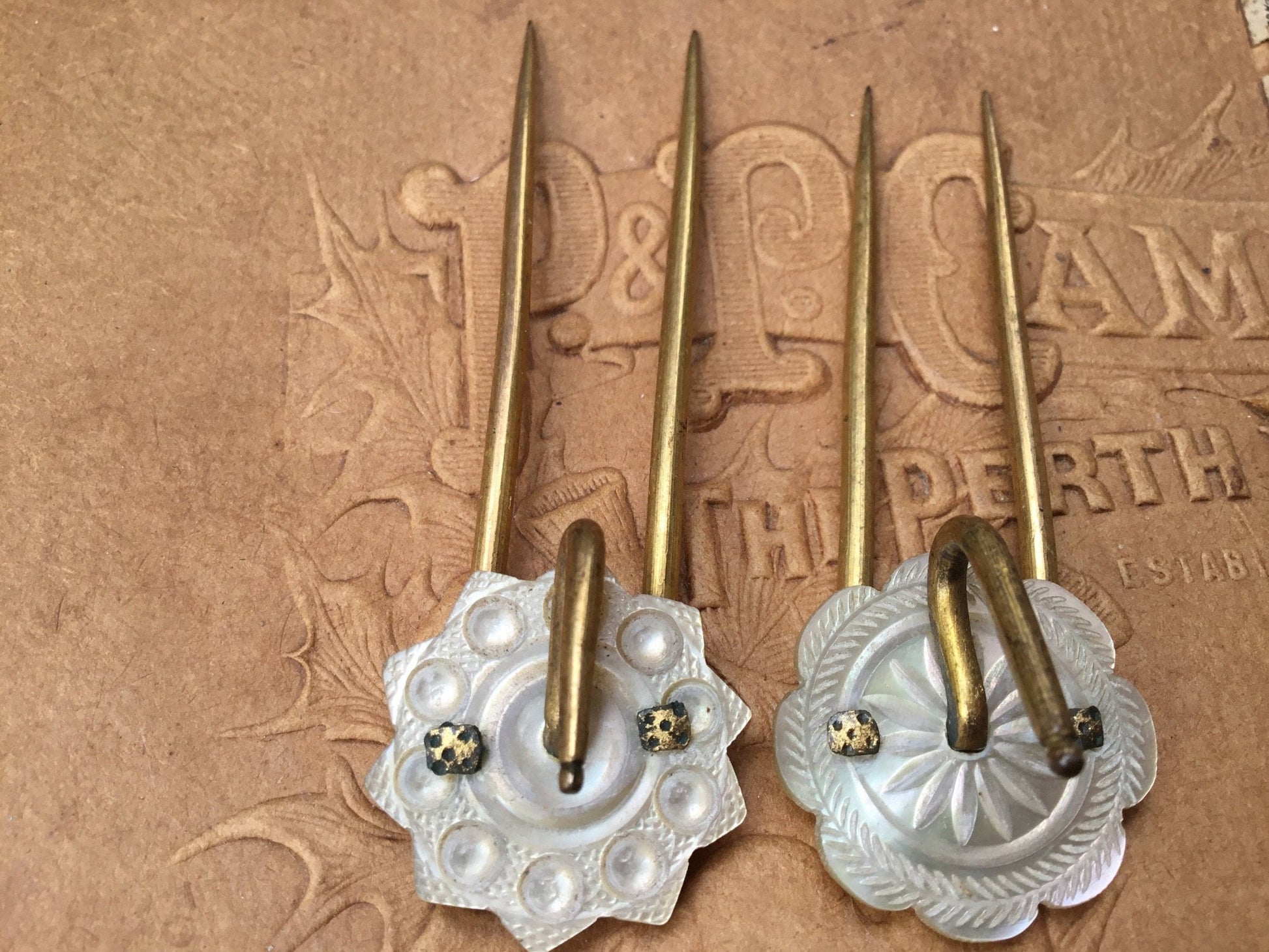 old coloured Hair pins with mother of pearl circular top on textured brown background - Splendid Vintage World