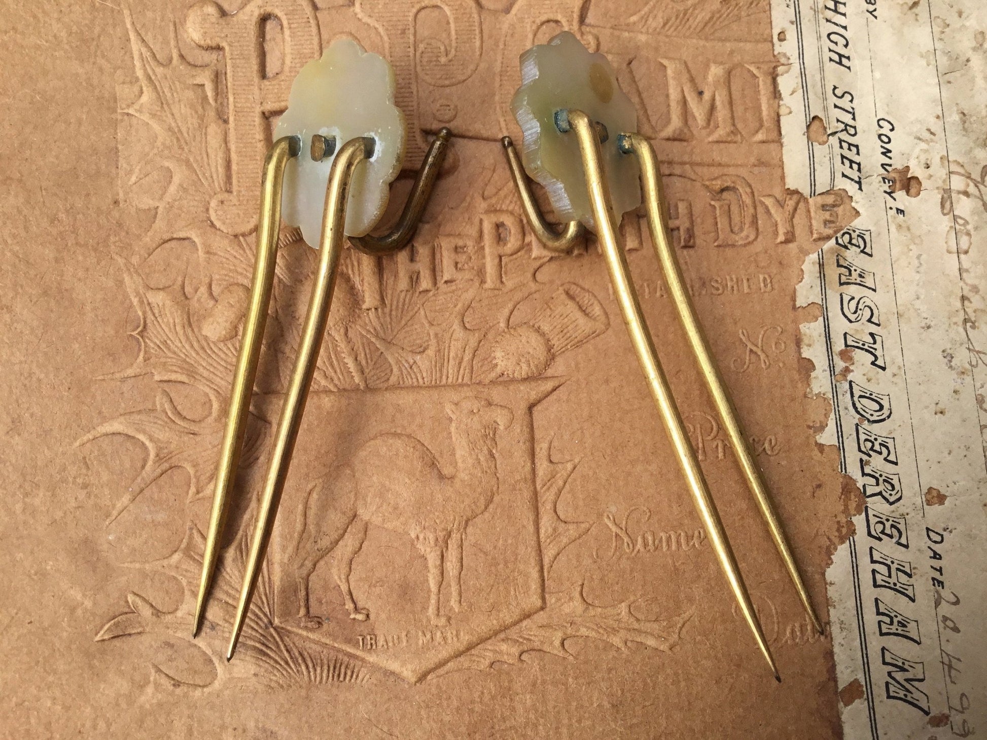 2 gold coloured Hair pins with mother of pearl circular top on textured brown background - Splendid Vintage World