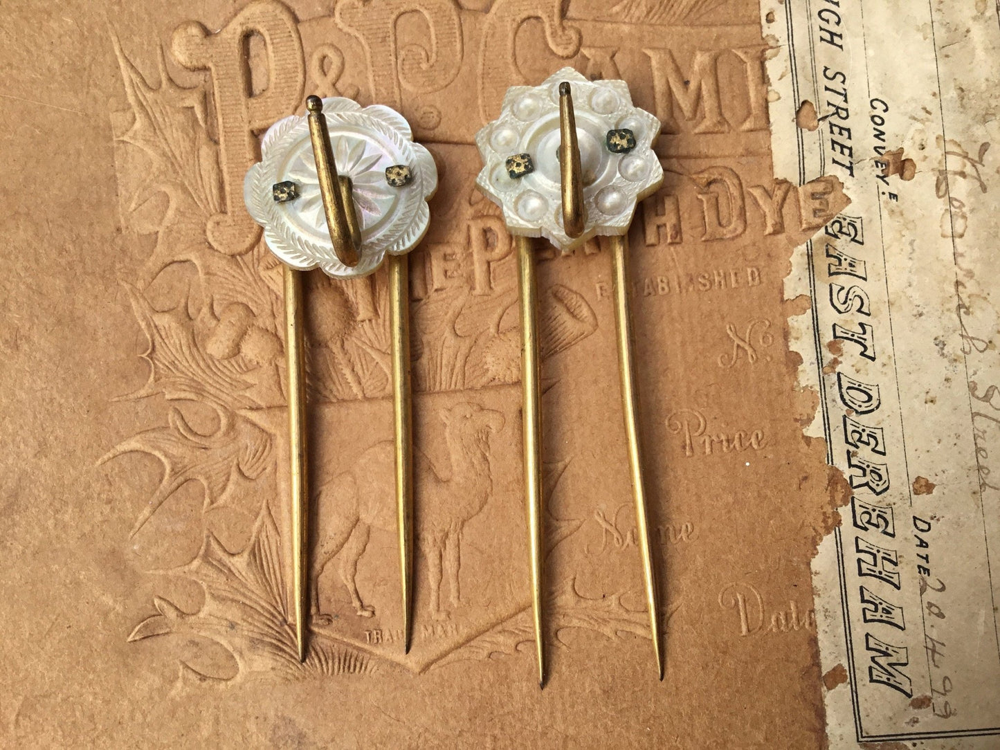 old coloured Hair pins with mother of pearl circular top on textured brown background - Splendid Vintage World