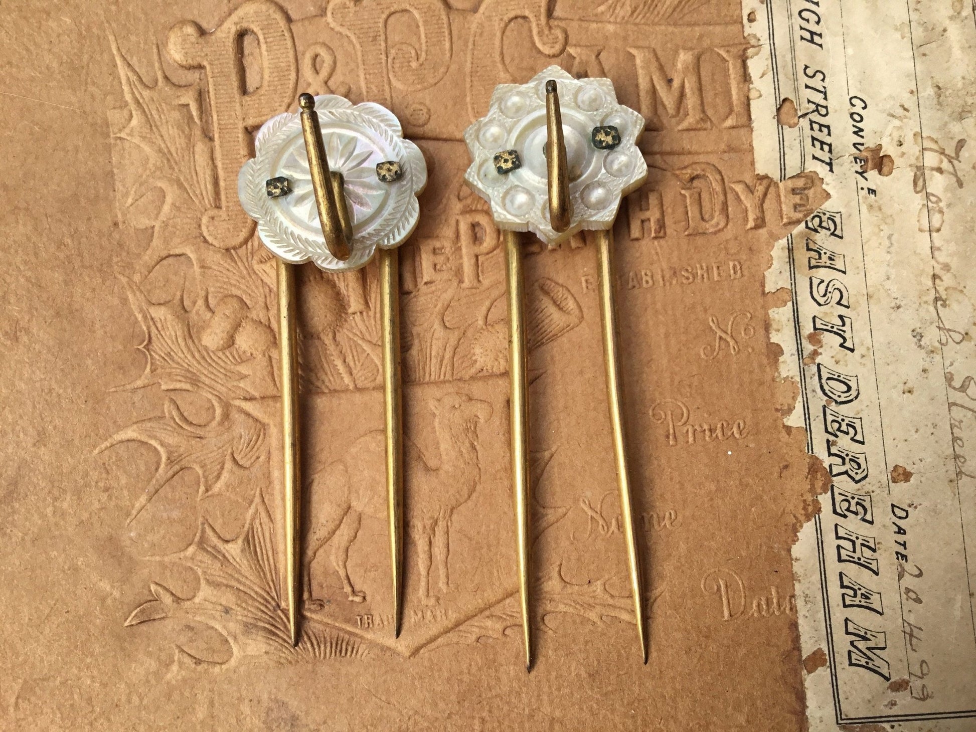 old coloured Hair pins with mother of pearl circular top on textured brown background - Splendid Vintage World