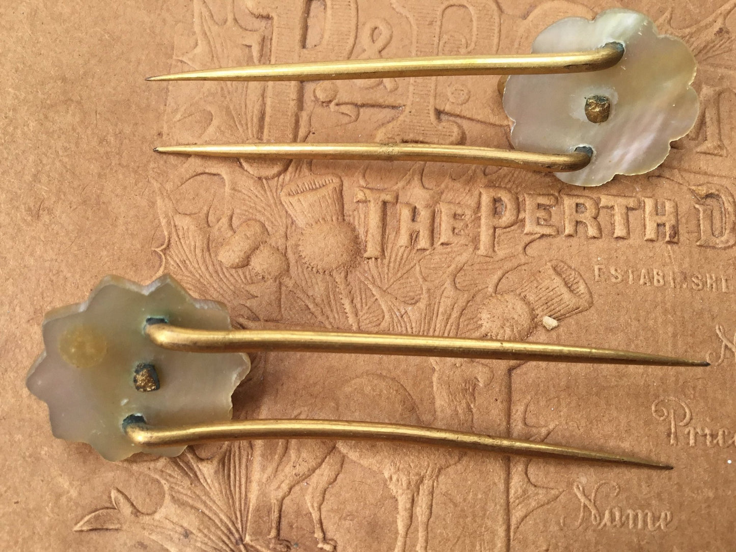 old coloured Hair pins with mother of pearl circular top on textured brown background - Splendid Vintage World