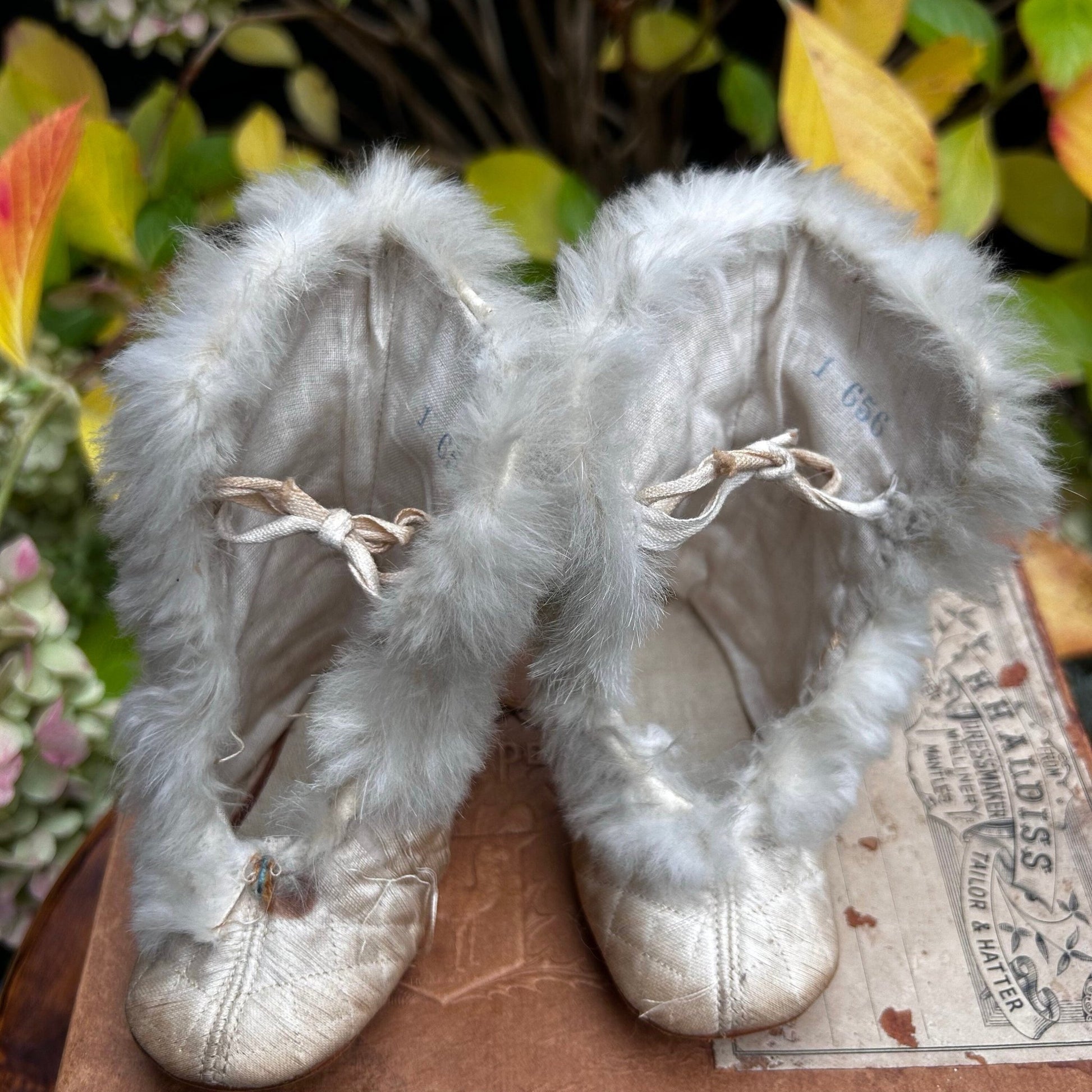 quilted textile fur lined silk baby boots on wooden surface with plants behind - Splendid Vintage World