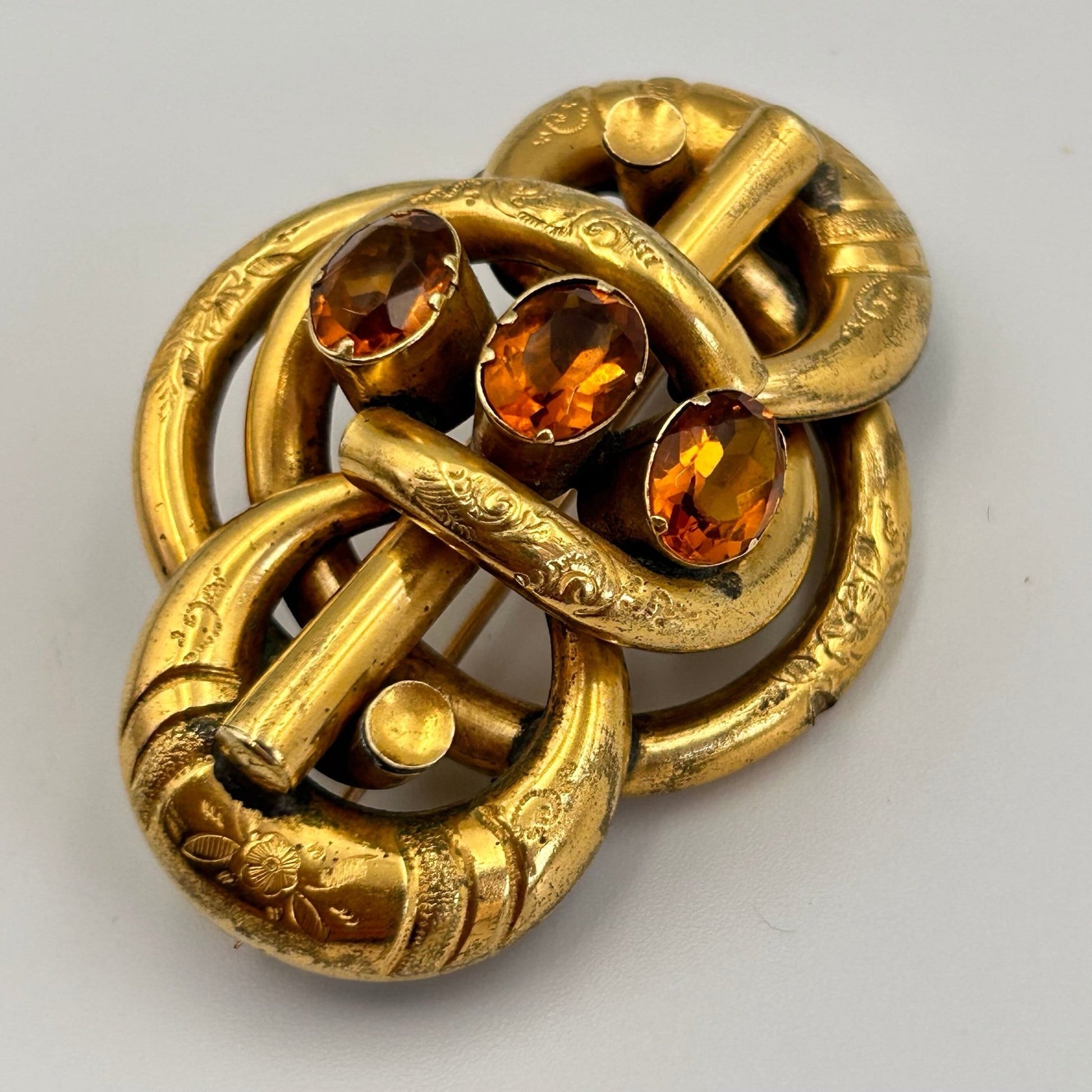 Victorian gold coloured brooch in lovers knot form, 3 oval citrine paste stones on light background - Splendid Vintage World
