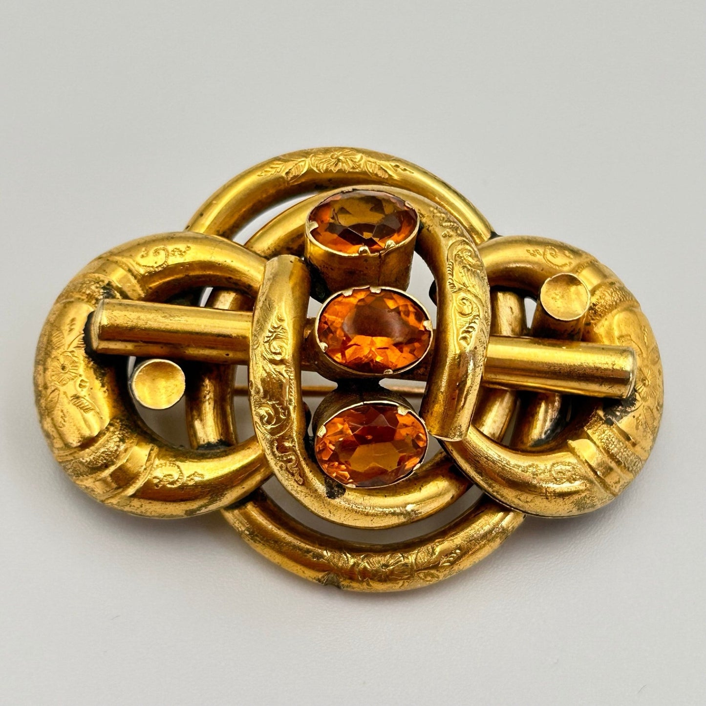Victorian gold coloured brooch in lovers knot form, 3 oval citrine paste stones on light background - Splendid Vintage World
