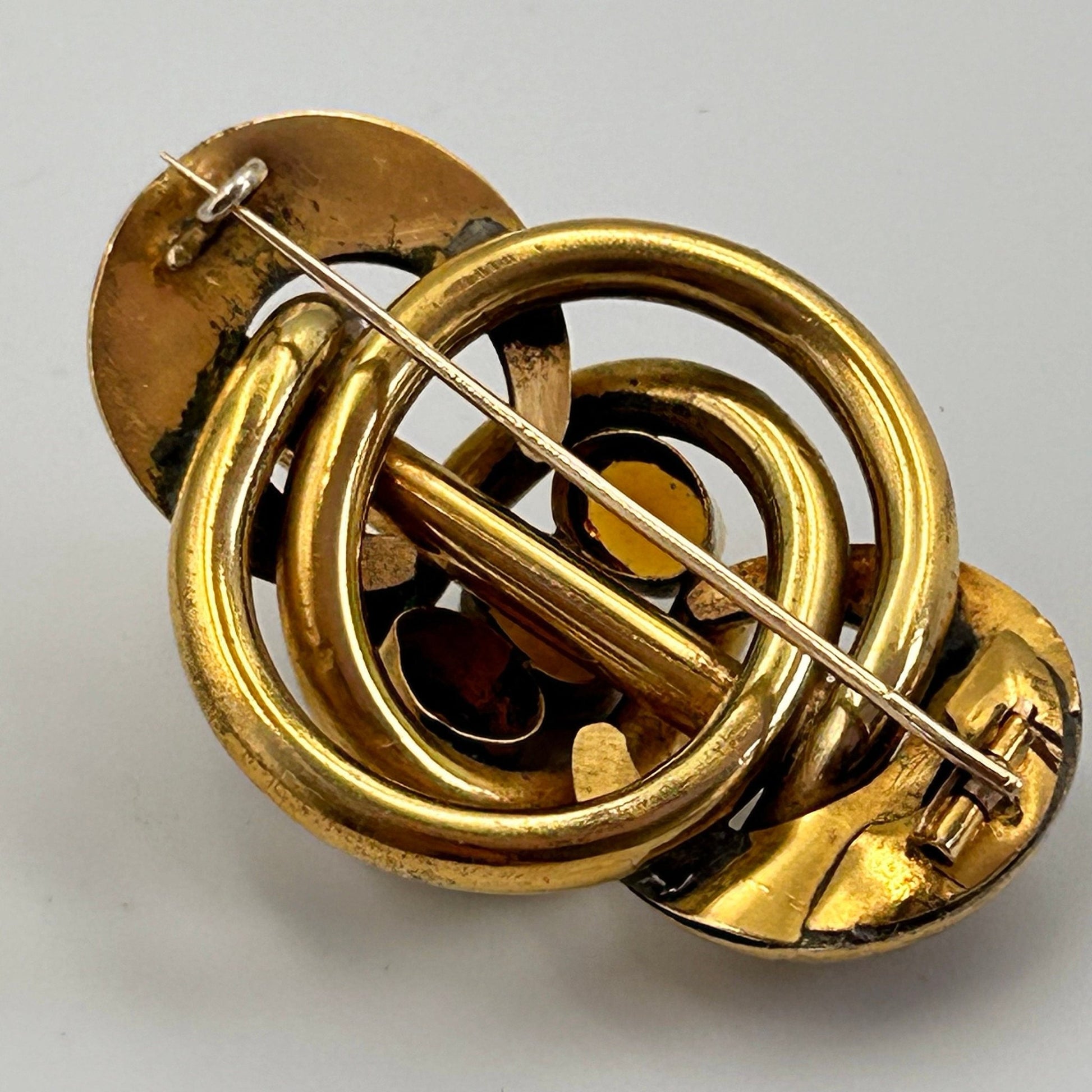 back of gold coloured lovers knot brooch on light background - Splendid Vintage World