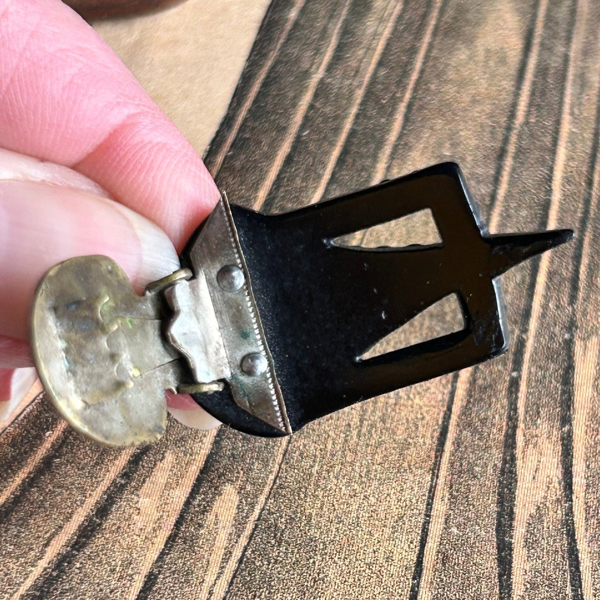 Back view of the metal clip of the dress clip held by a hand above an illustration- Splendid Vintage World