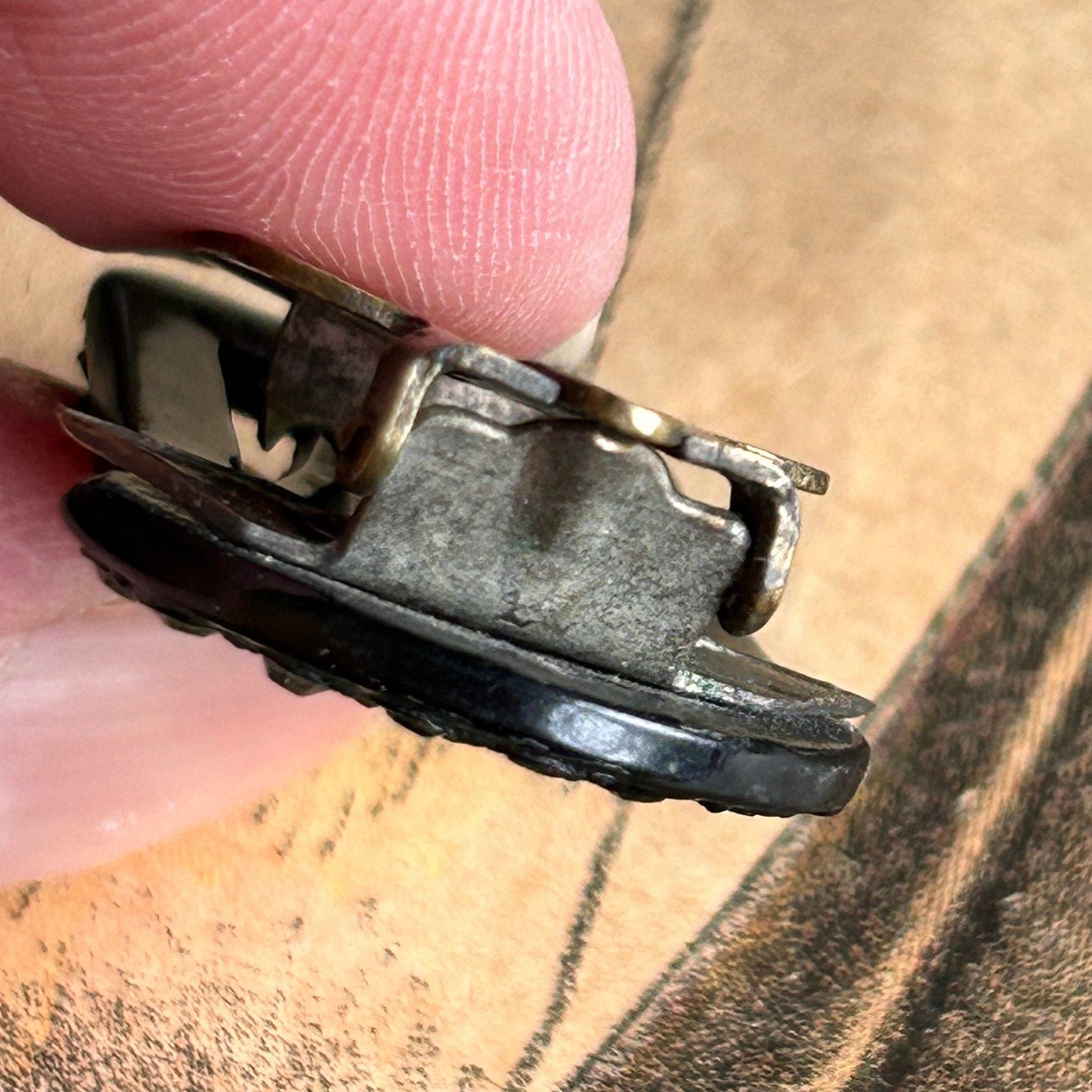 side view of an Art Deco 1930s dress clip in black glass being held above an old illustration- Splendid Vintage World