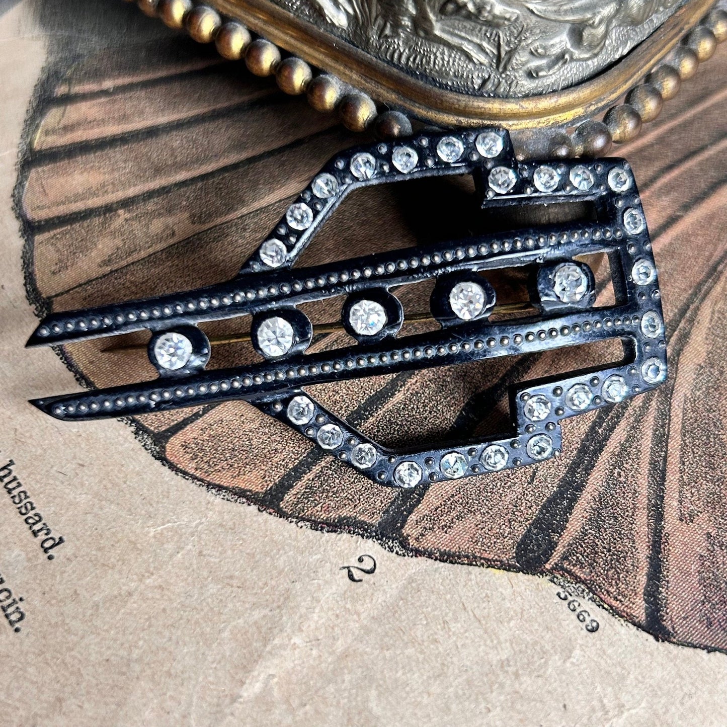 Art Deco diamanté and fine pin detail on hat pin on illustrated magazine background - Splendid Vintage World