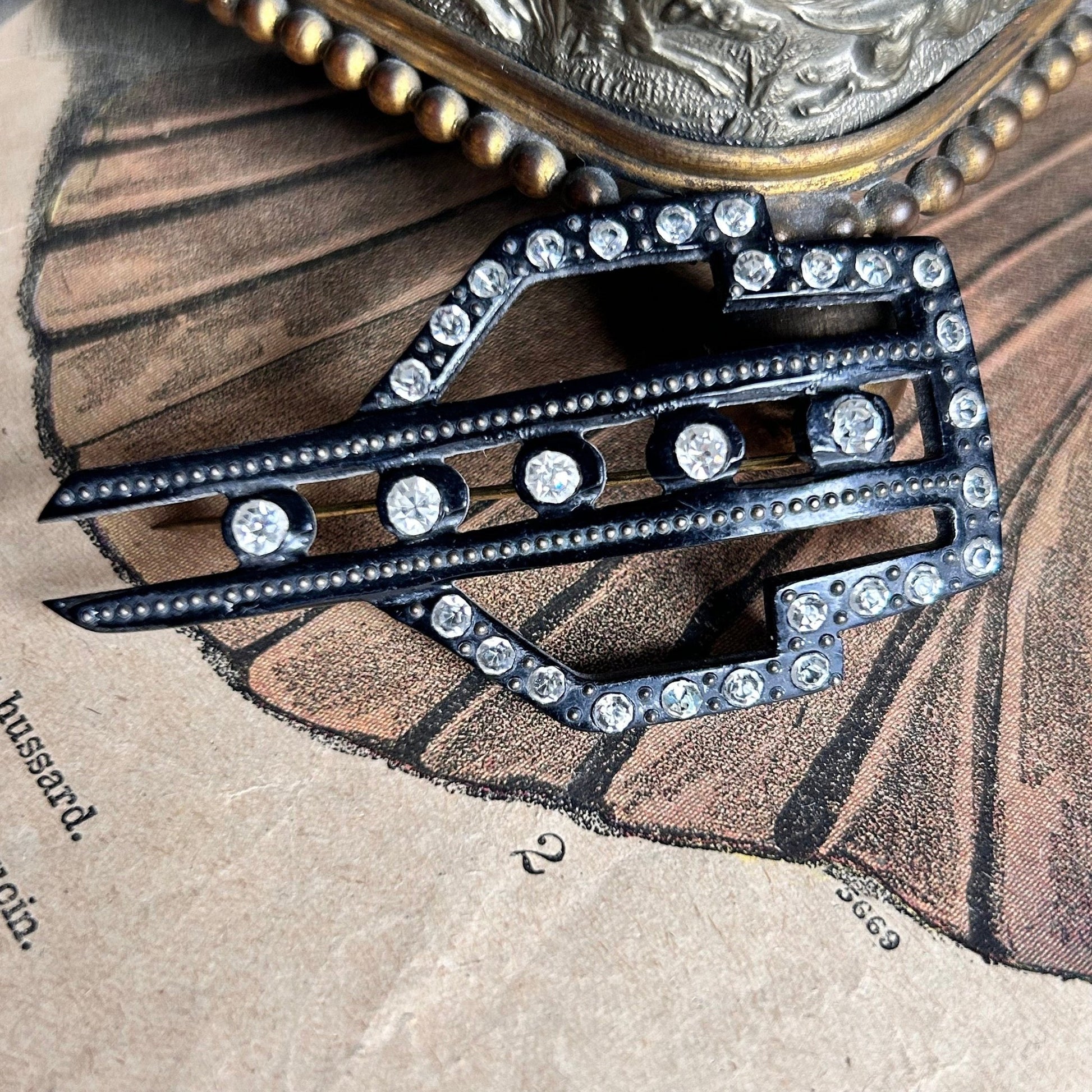 Art Deco diamanté and fine pin detail on hat pin on illustrated magazine background - Splendid Vintage World
