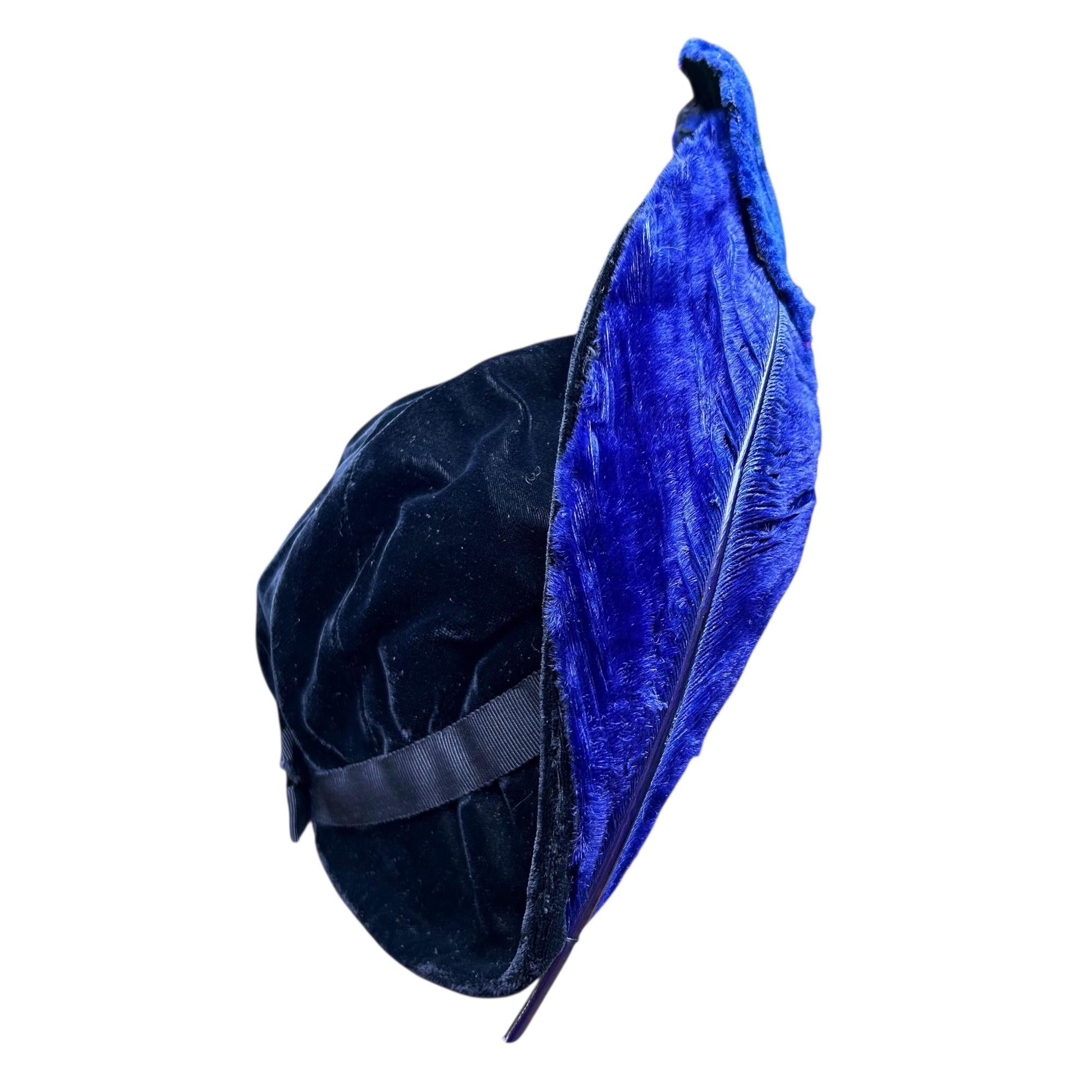 side view of blue ostrich feather upright brim & black velvet crown of a hat on white background - Splendid Vintage World
