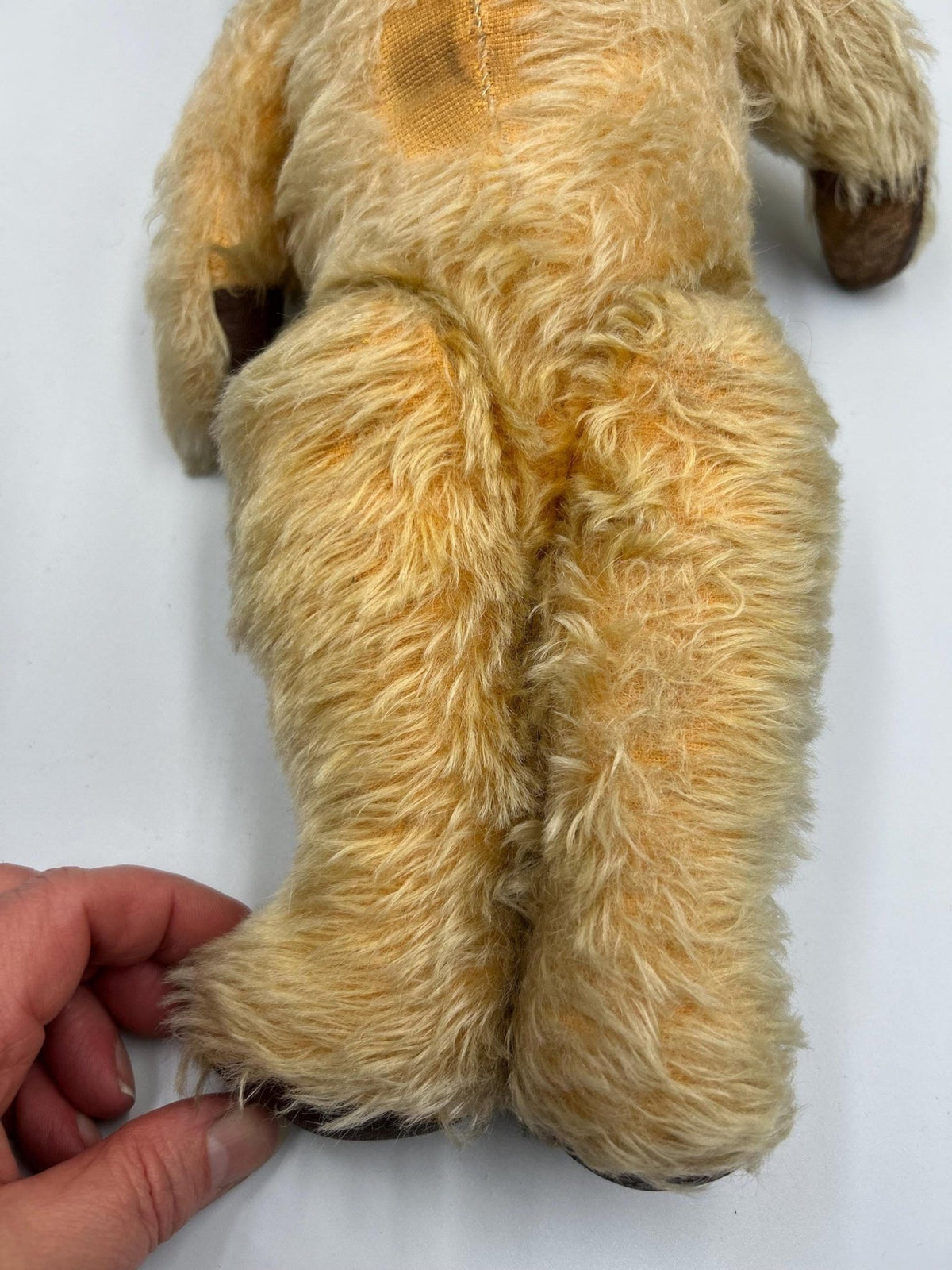 Vintage teddy bear legs with wear held by hand  - Splendid Vintage World