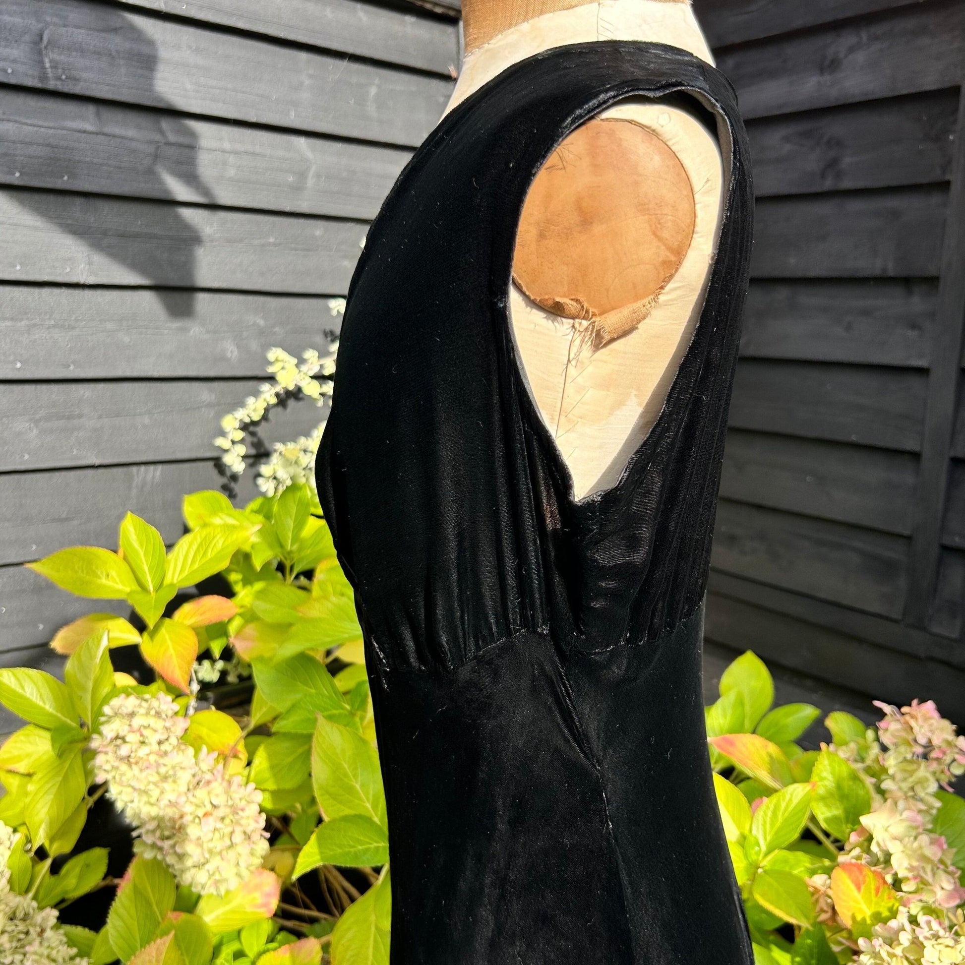 side view of 1930s black velvet sleeveless dress bodice in garden background - Splendid Vintage World