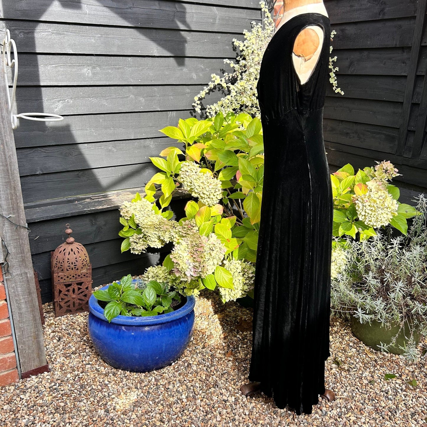 side view of 1930s black velvet bias cut dress on mannequin on gravel in garden - Splendid Vintage World