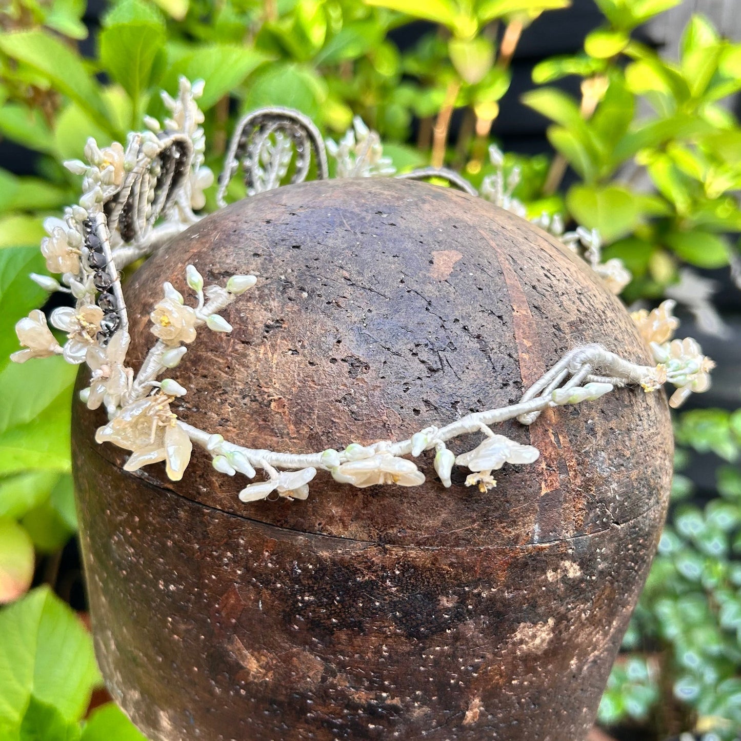 bridal crown tiara of diamanté, wax flowers & buds on wooden hat block with greenery behind - Splendid Vintage World