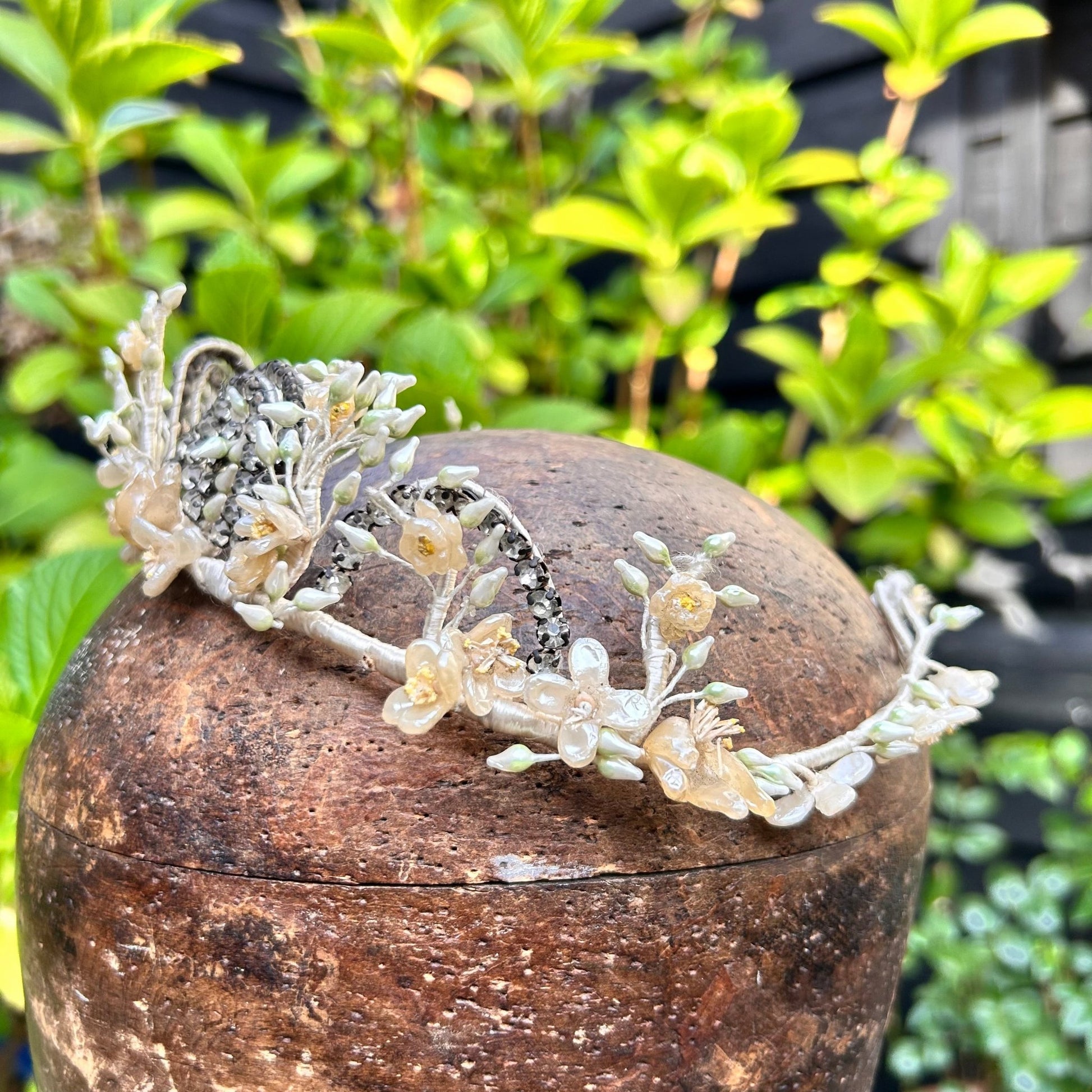 bridal crown tiara of diamanté, wax flowers & buds on wooden hat block with greenery behind - Splendid Vintage World