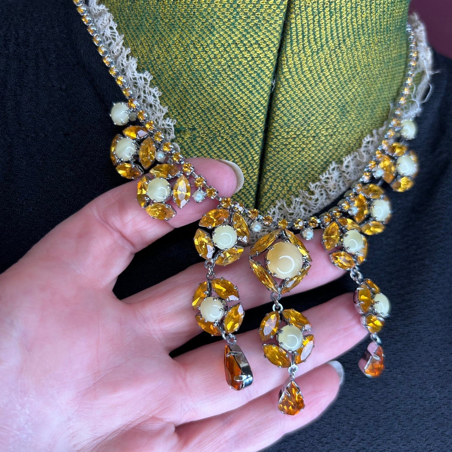 Citrine colour Necklace With Floral Droplets & Faux Pearls in hand on black dress & green mannequin - Splendid Vintage World