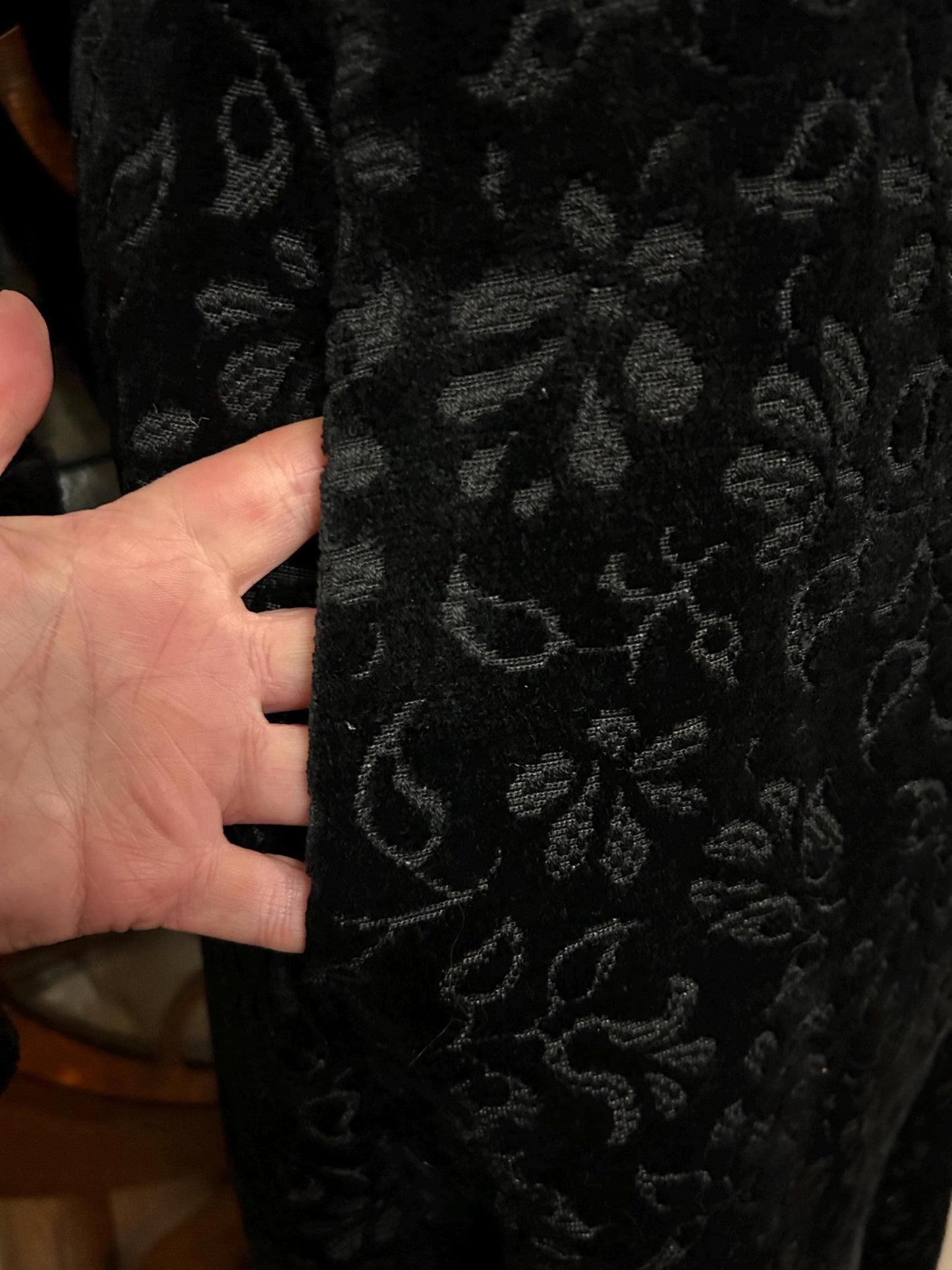 Vintage black floral velvet coat pocket with hand partially inserted showing design and position - Splendid Vintage World