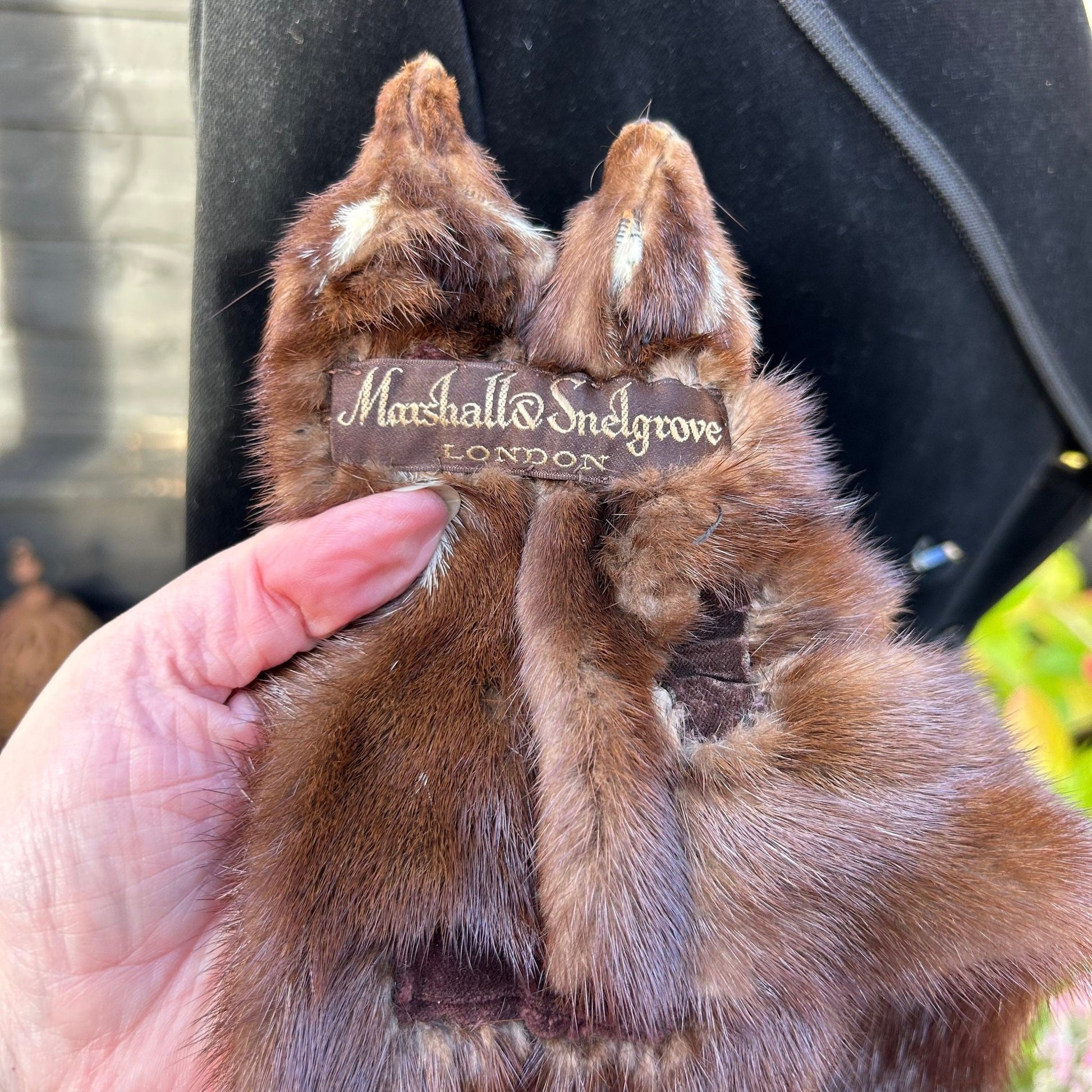Vintage mink fur stole tippet in hand showing Marshall Snelgrove label against black coat & greenery - Splendid Vintage World
